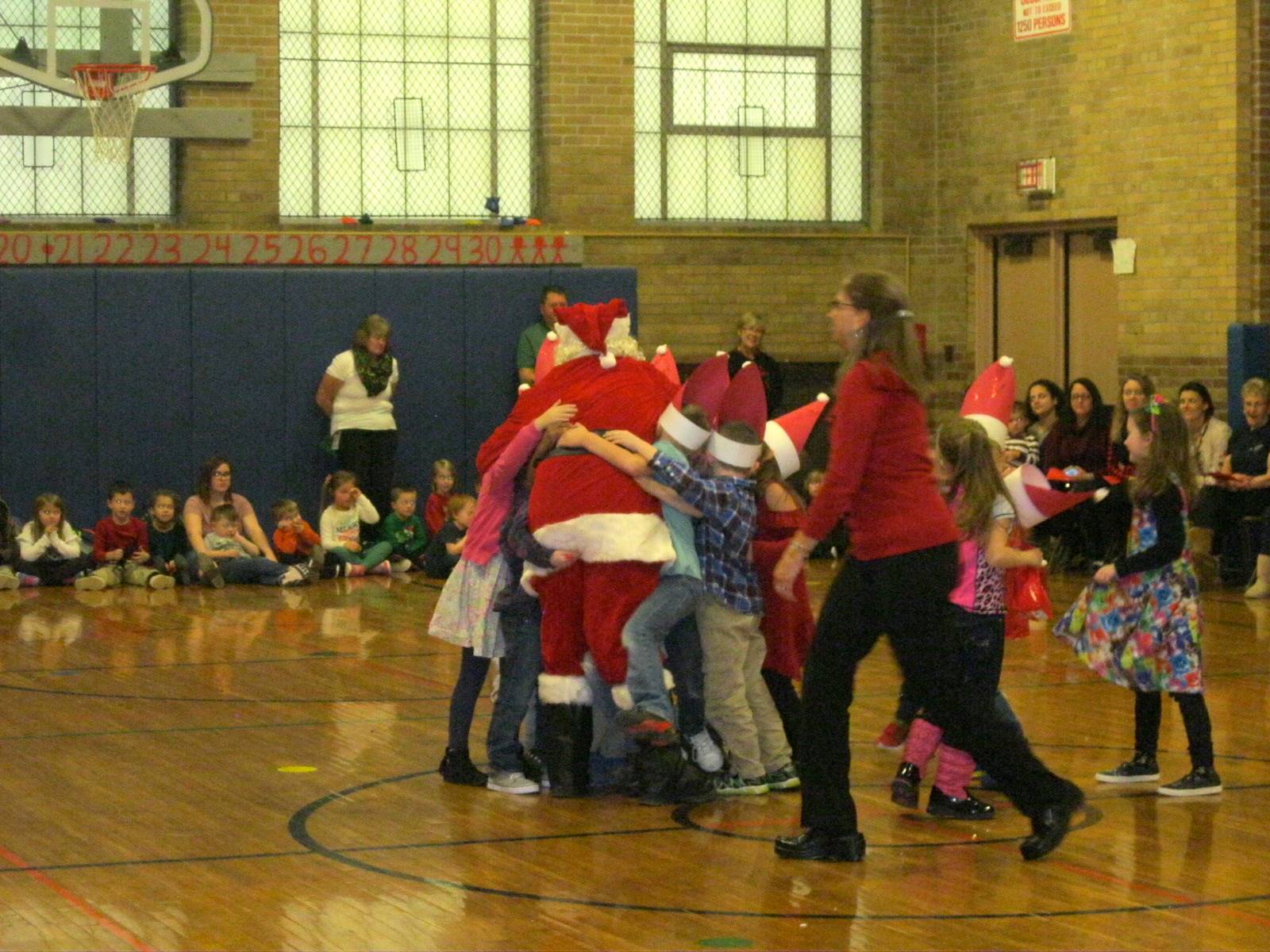 Mrs. Maynard and students rush to give Santa a hug.