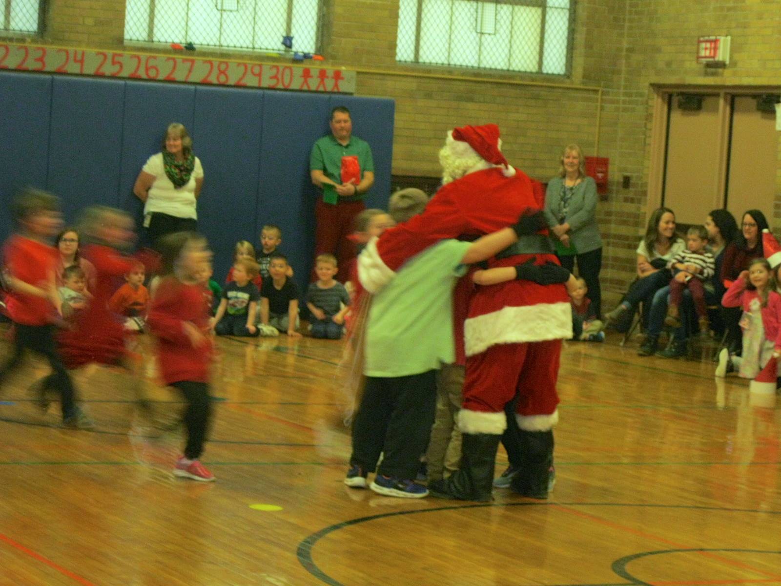 Santa gets a group hug from students.