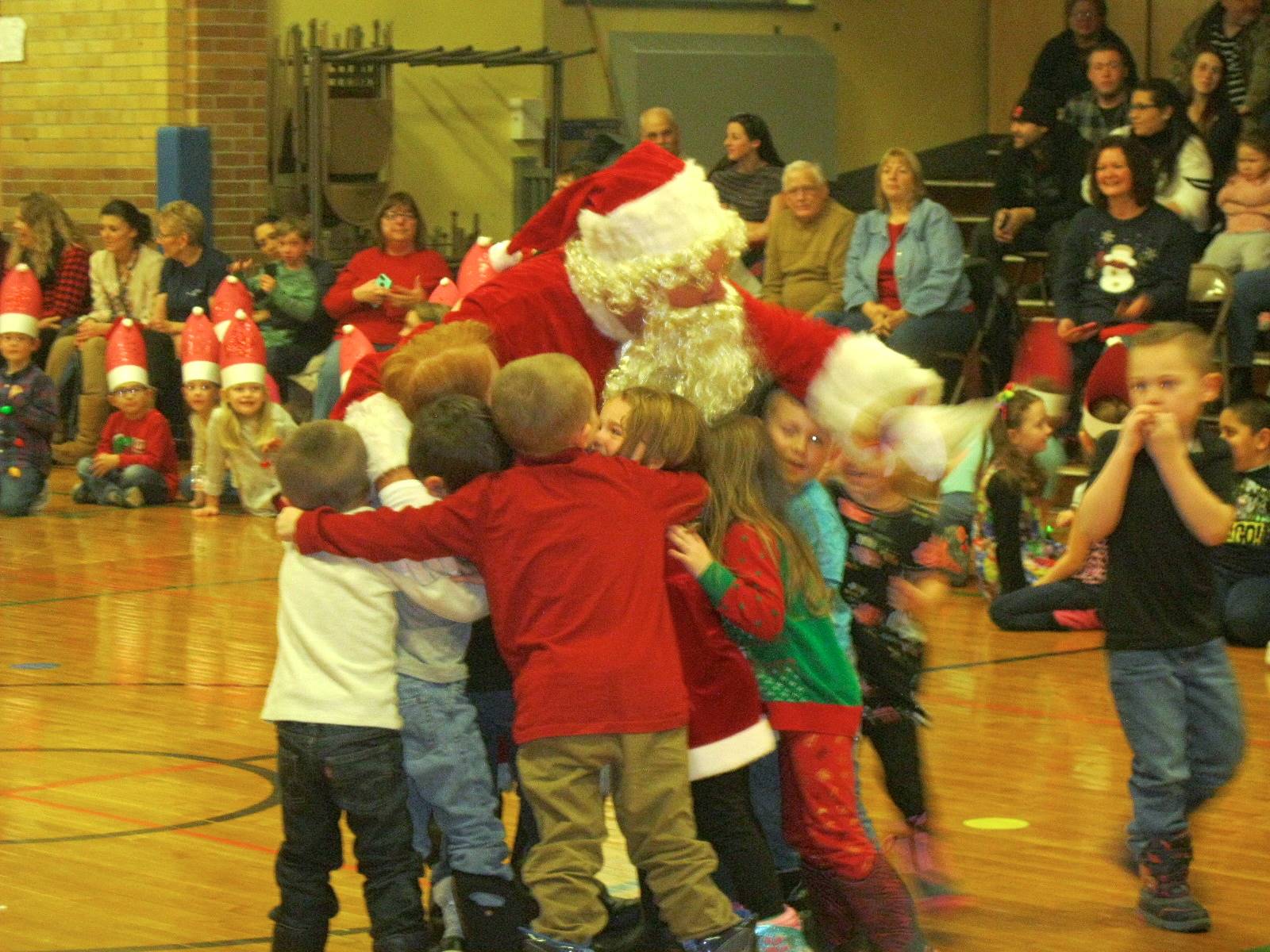 Santa hugs students.