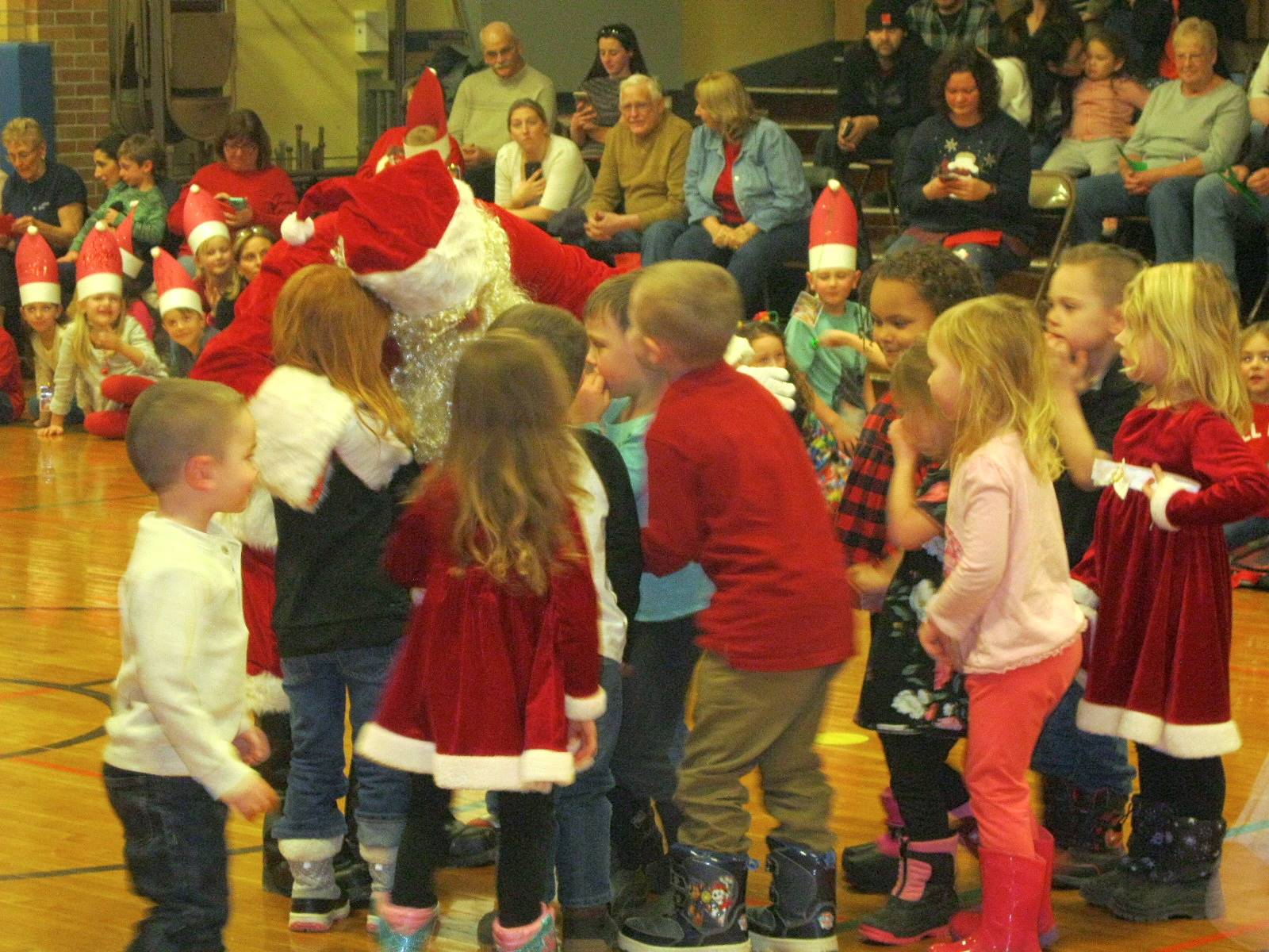 Santa hugs students.