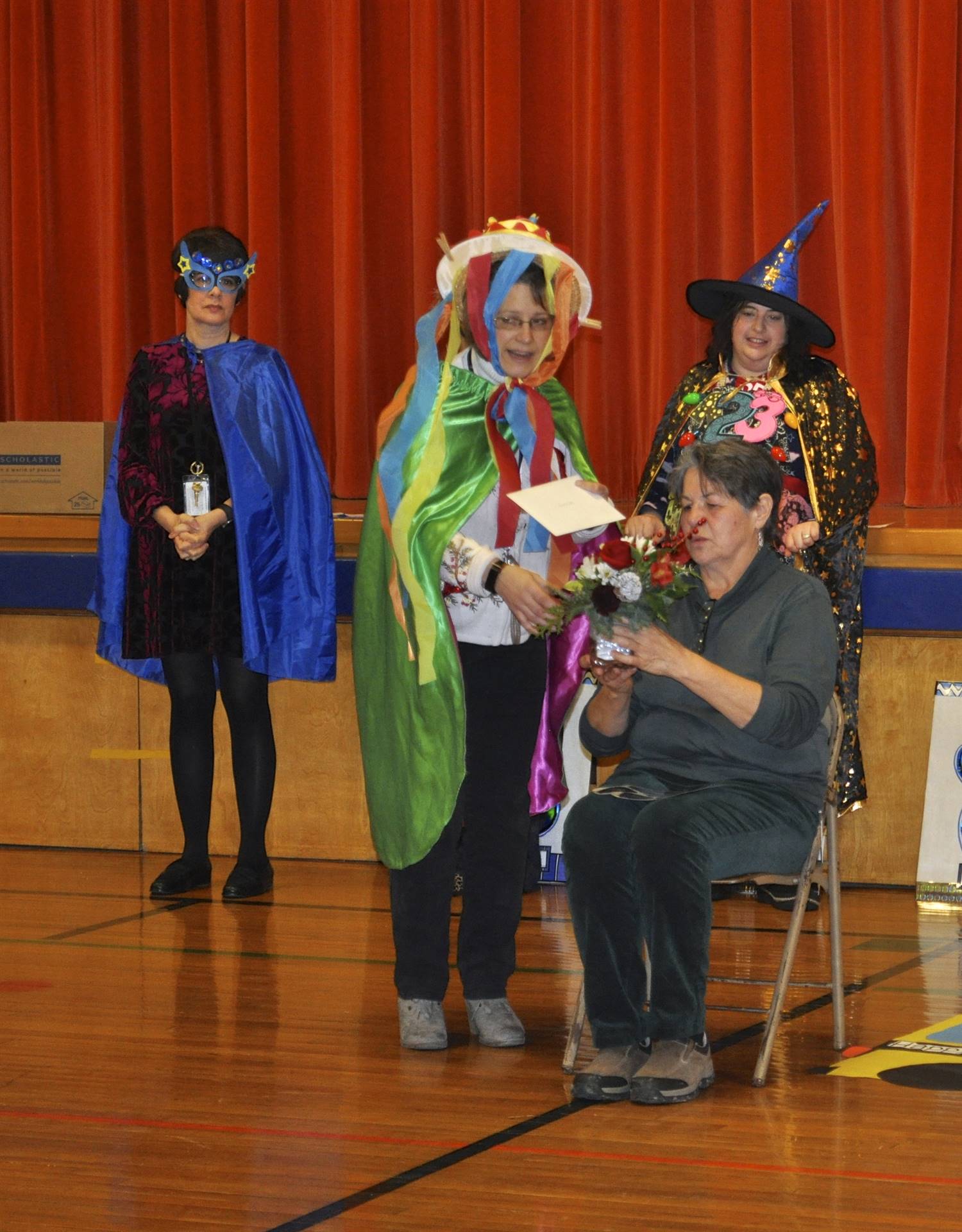 Birthday Club Queen presents Mrs. Butcher with a flower arrangement.