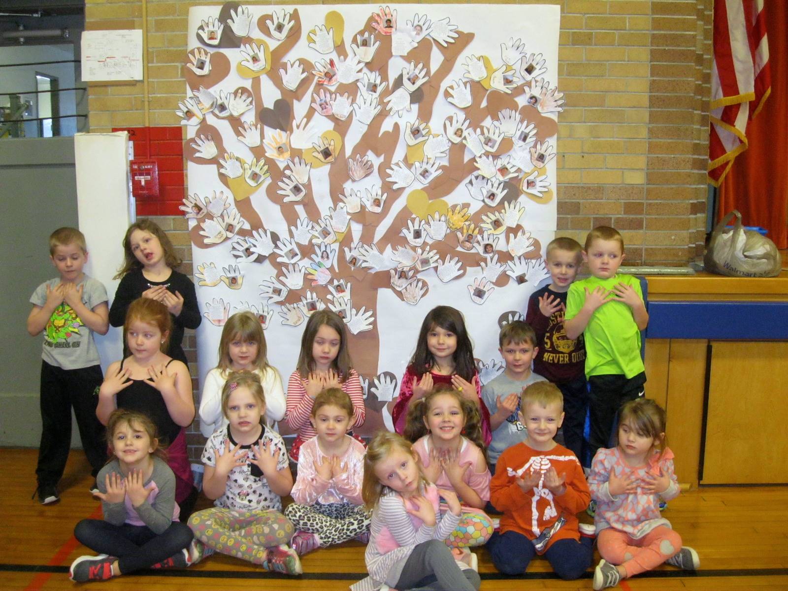 Students in front of a tree made out of hands.