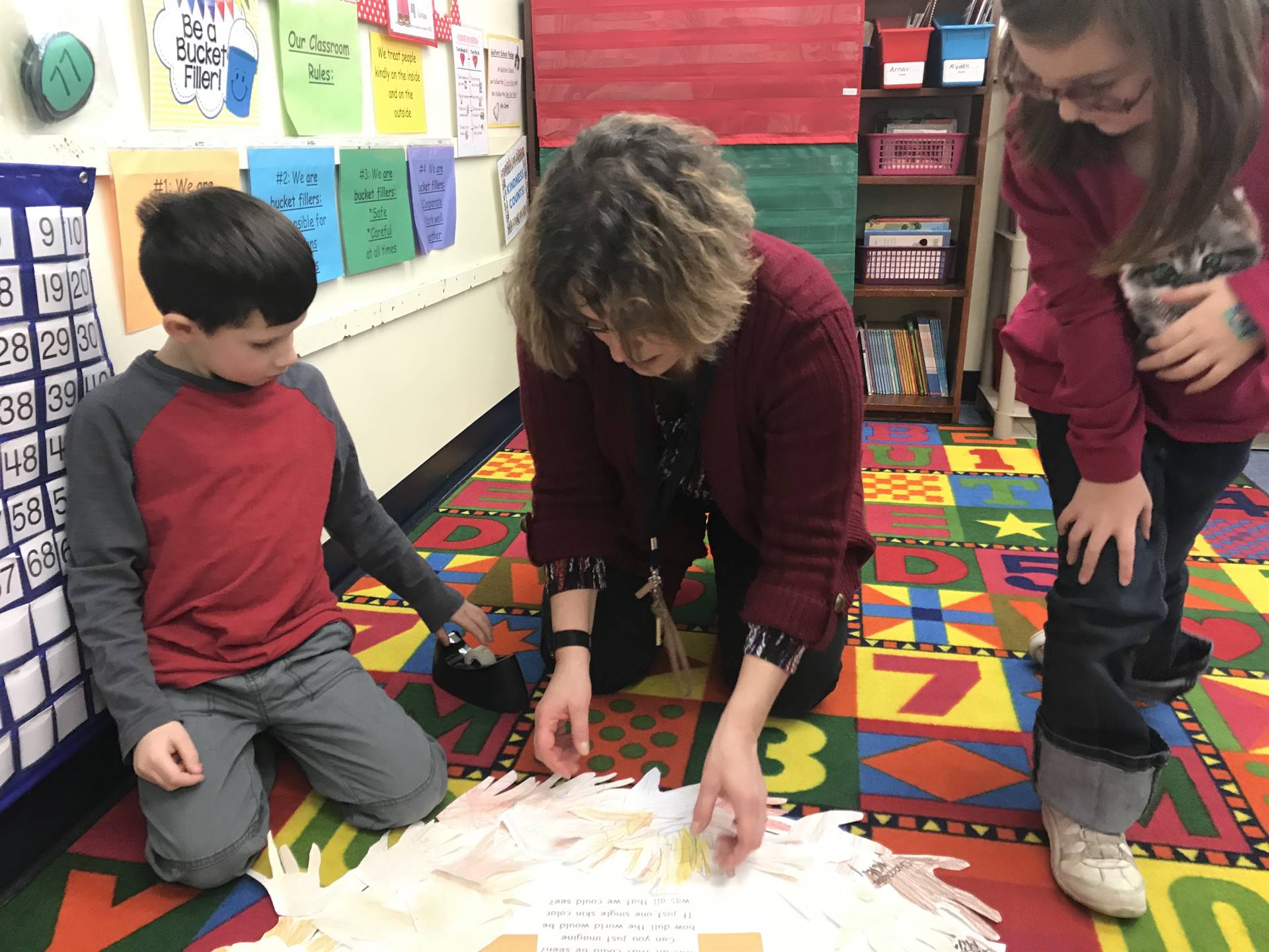 Counselor and students create a wreath skin-colored hands.