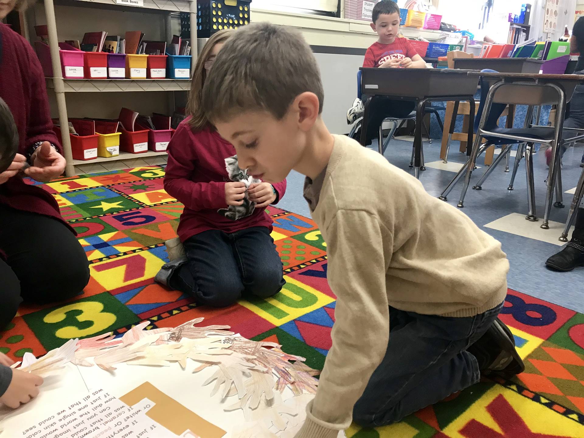 A student adds their colored hand to a wreath of hands.