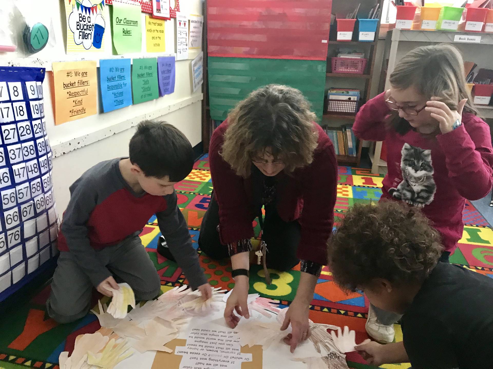 Counselor and students create a wreath skin-colored hands.