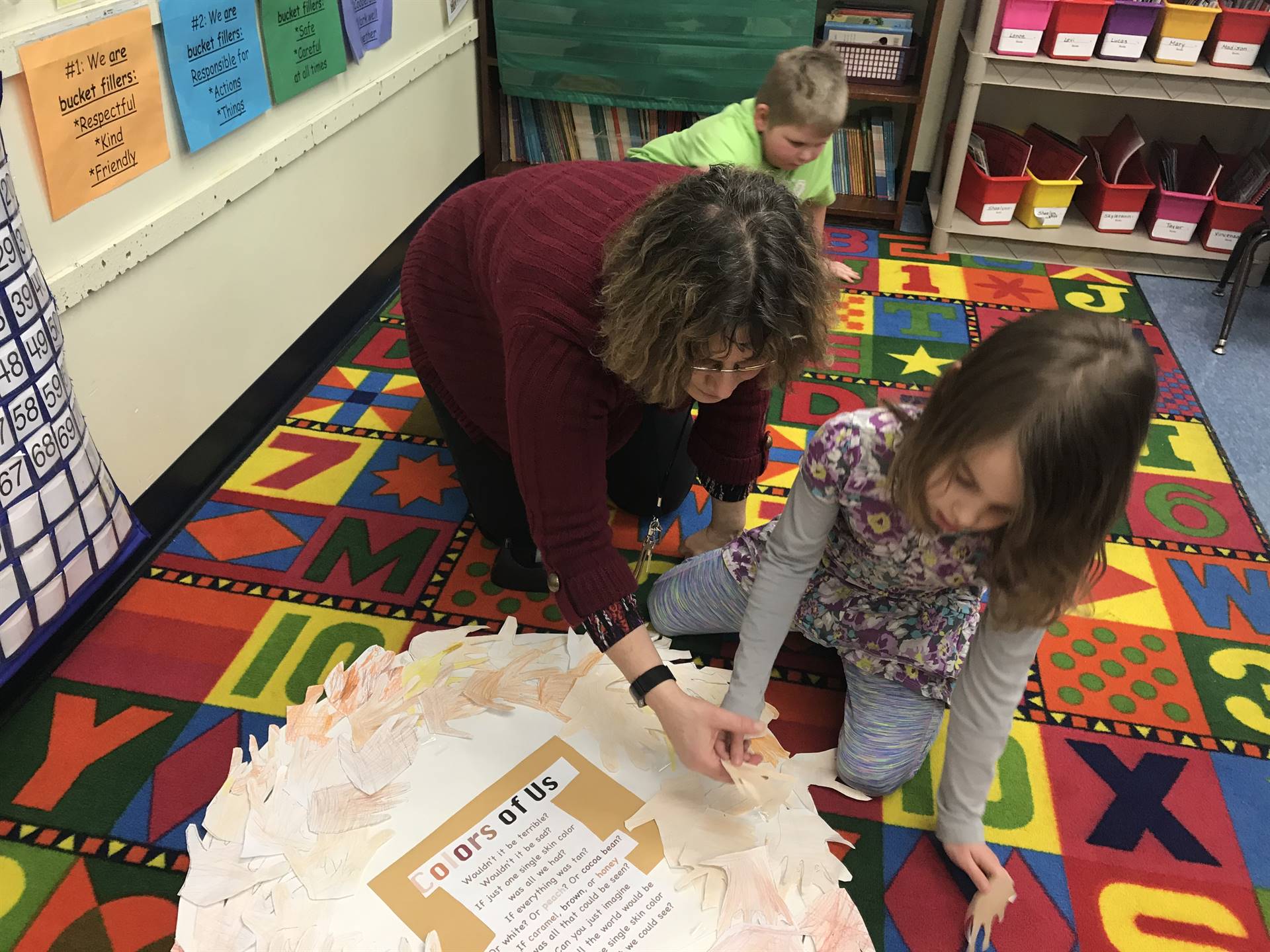 Counselor and students create a wreath skin-colored hands.