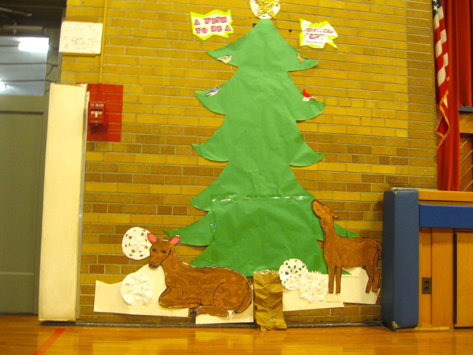 A bulletin board outline of an outdoor tree and deer.