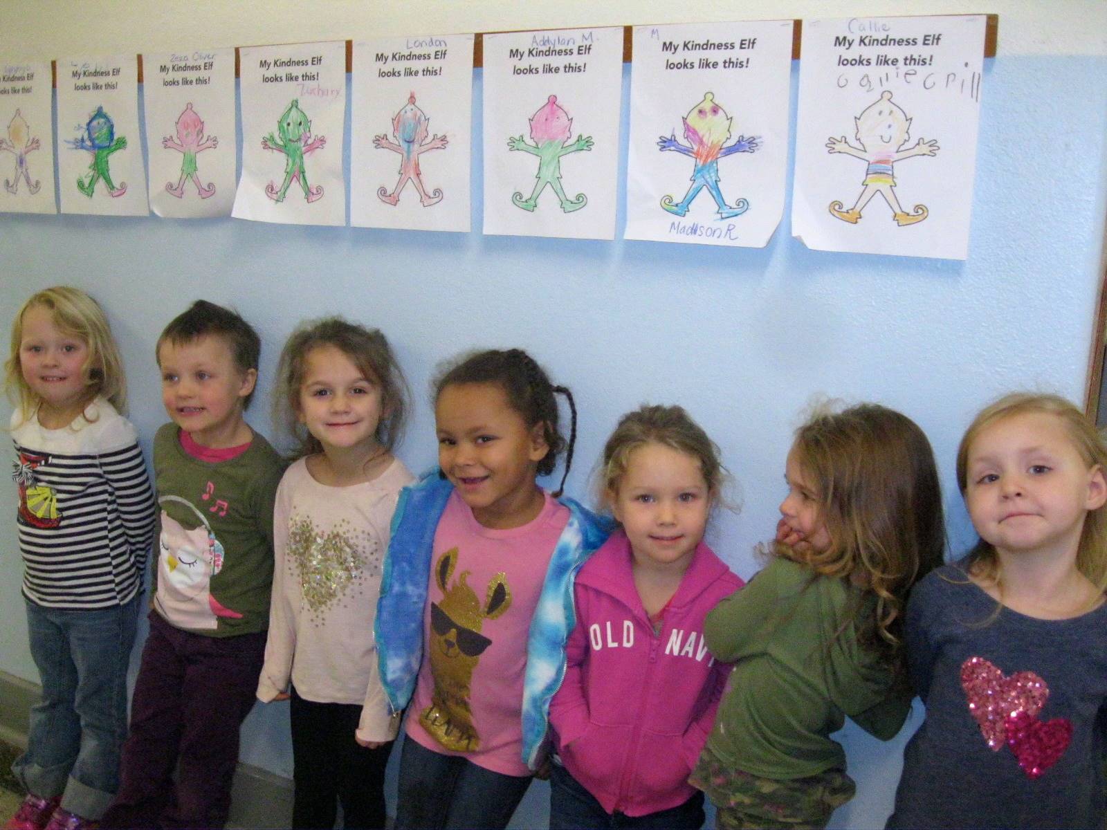 Students stand next to their Kindness Elf portraits.