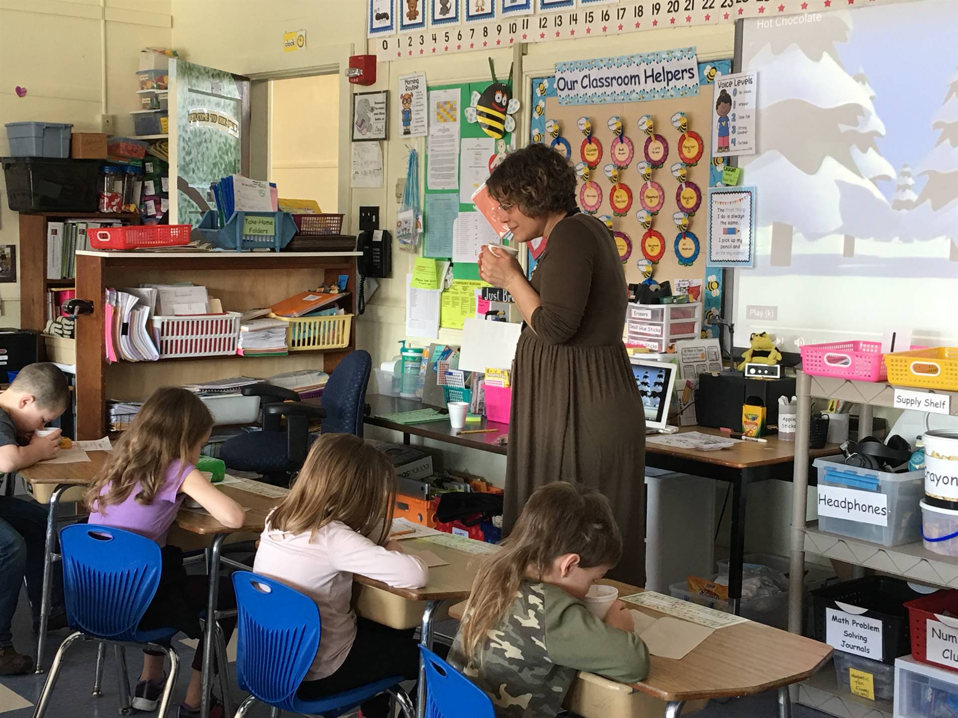 Mrs. Seiler and first graders hold hot cocoa cups.