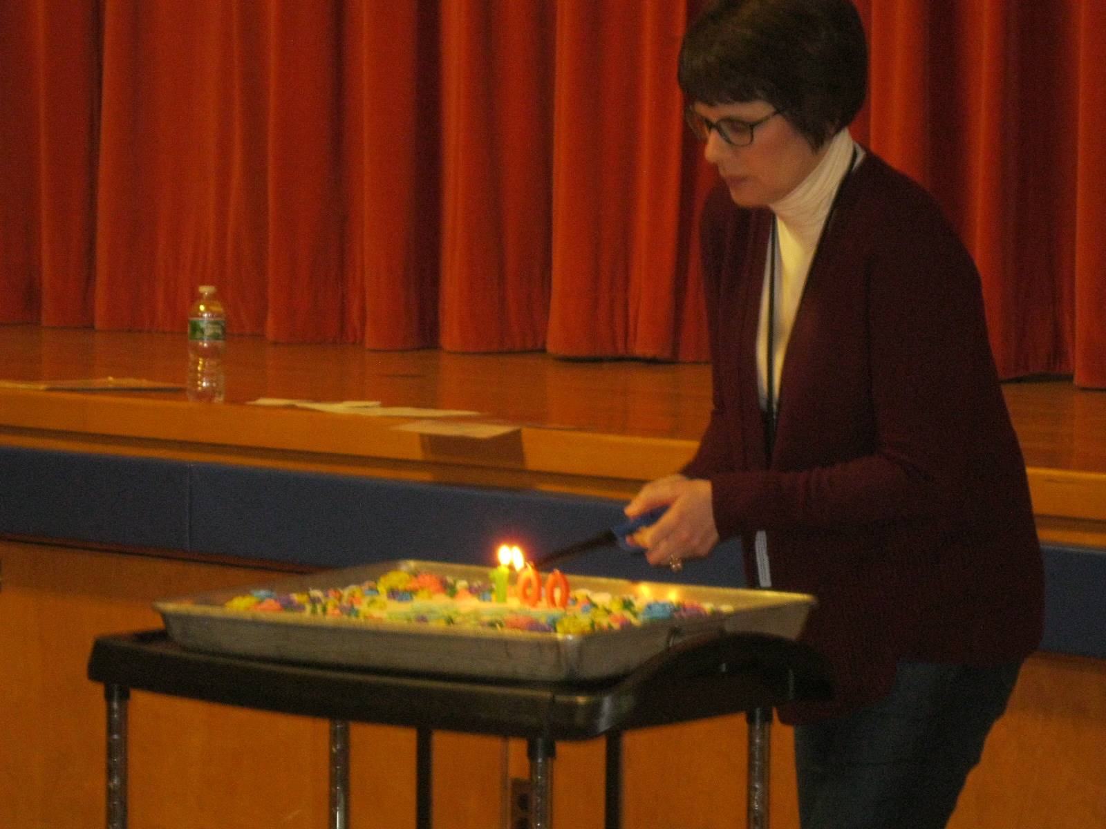 Teacher lights Zero's cake.