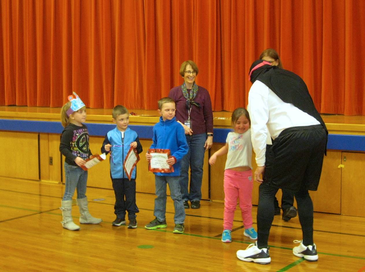 Zero the Hero shakes a students hand and students watch.