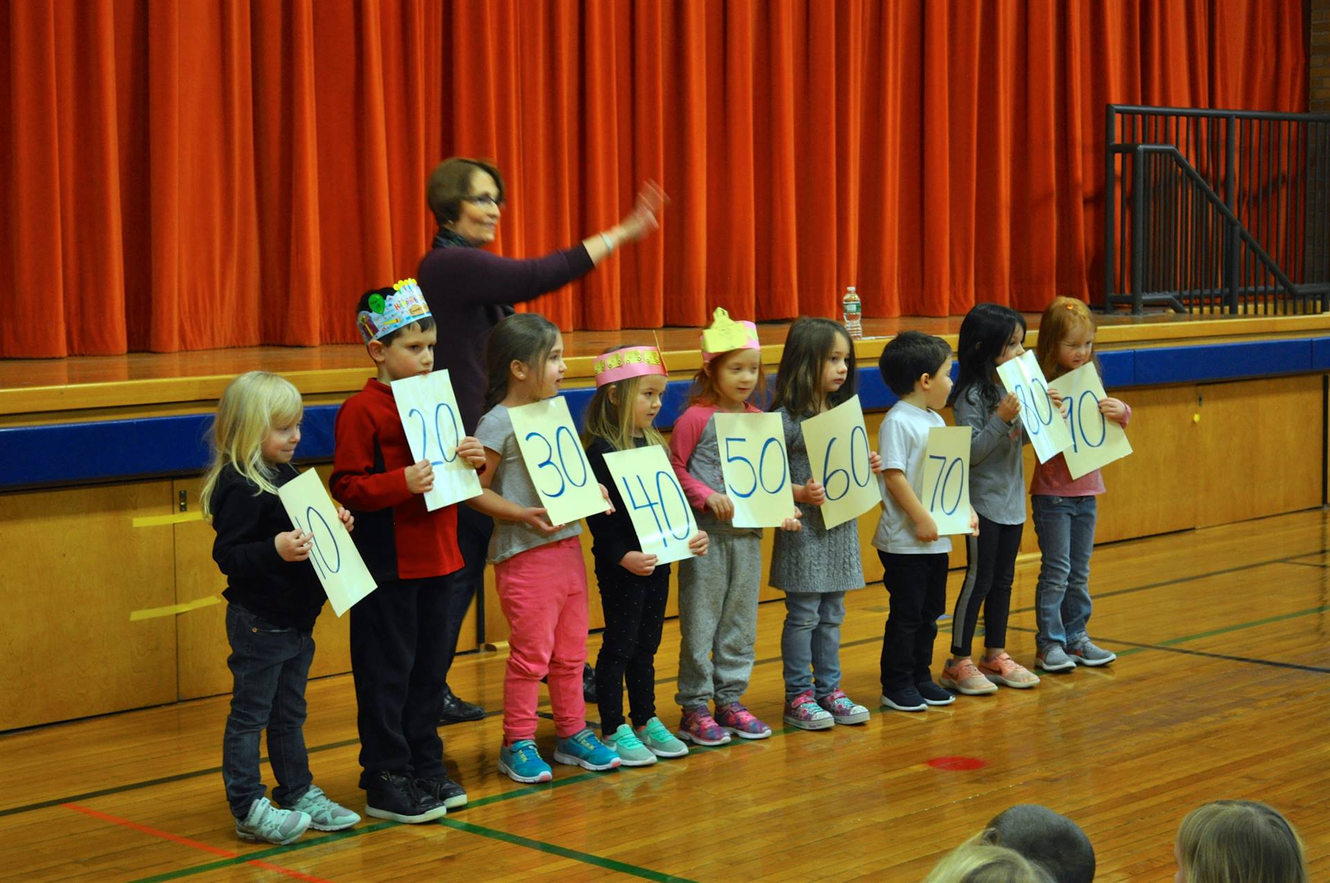 Teacher and students holding signs counting to 100 by 10's.