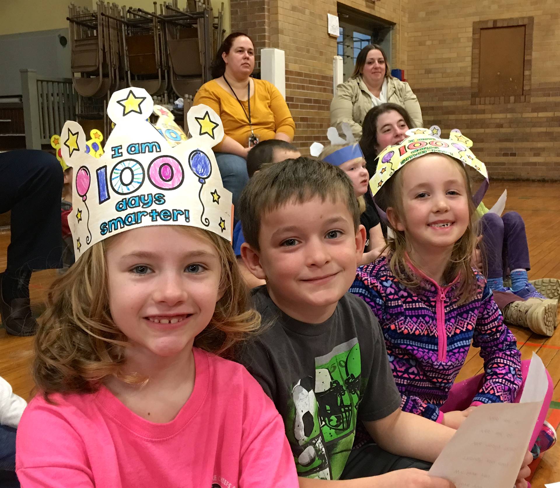 3 students wearing 100 hats.