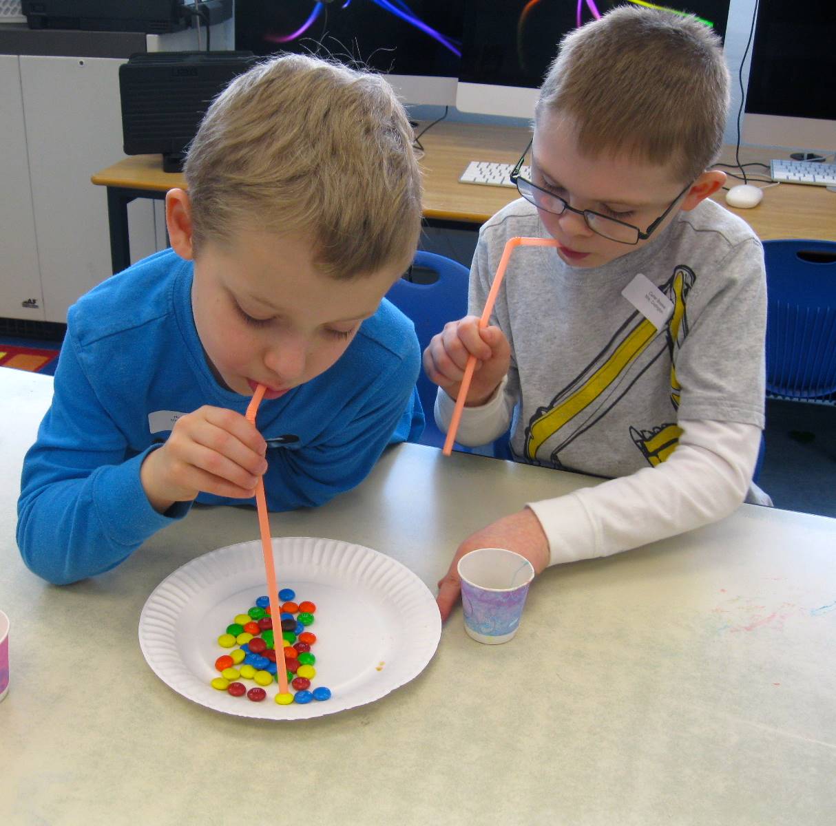 2 students using straws to move M&Ms