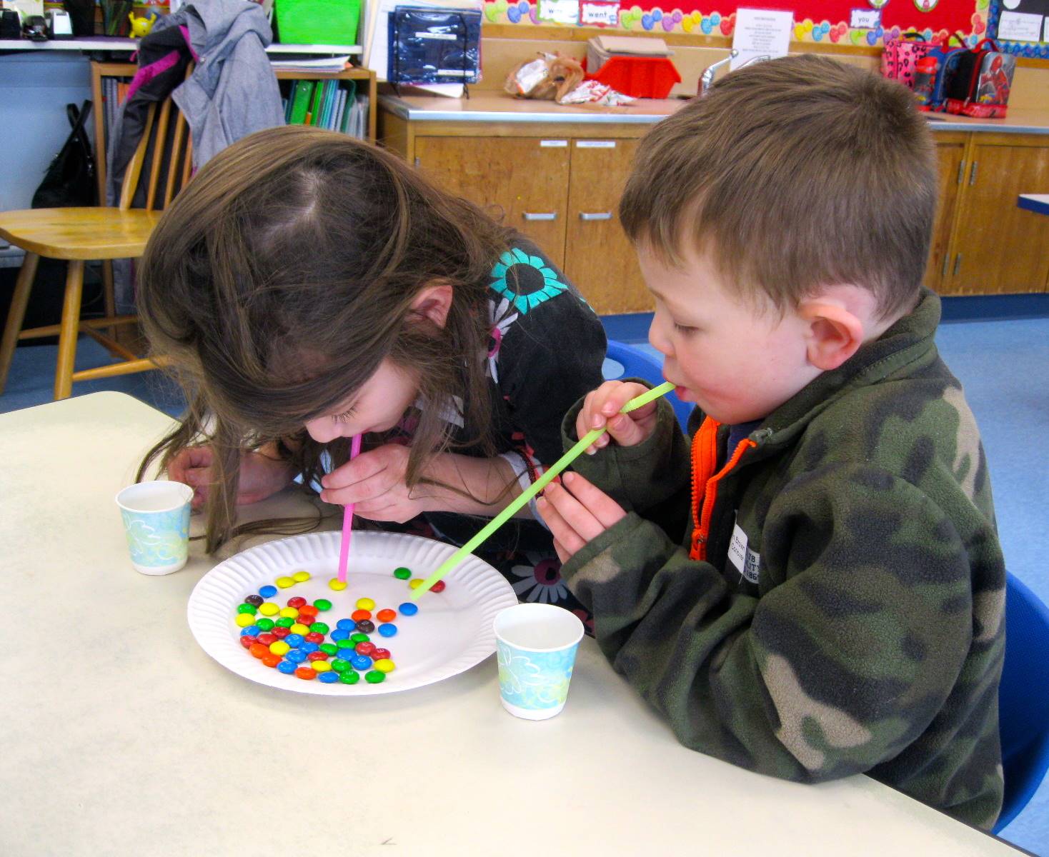 2 students using straws to move M&Ms