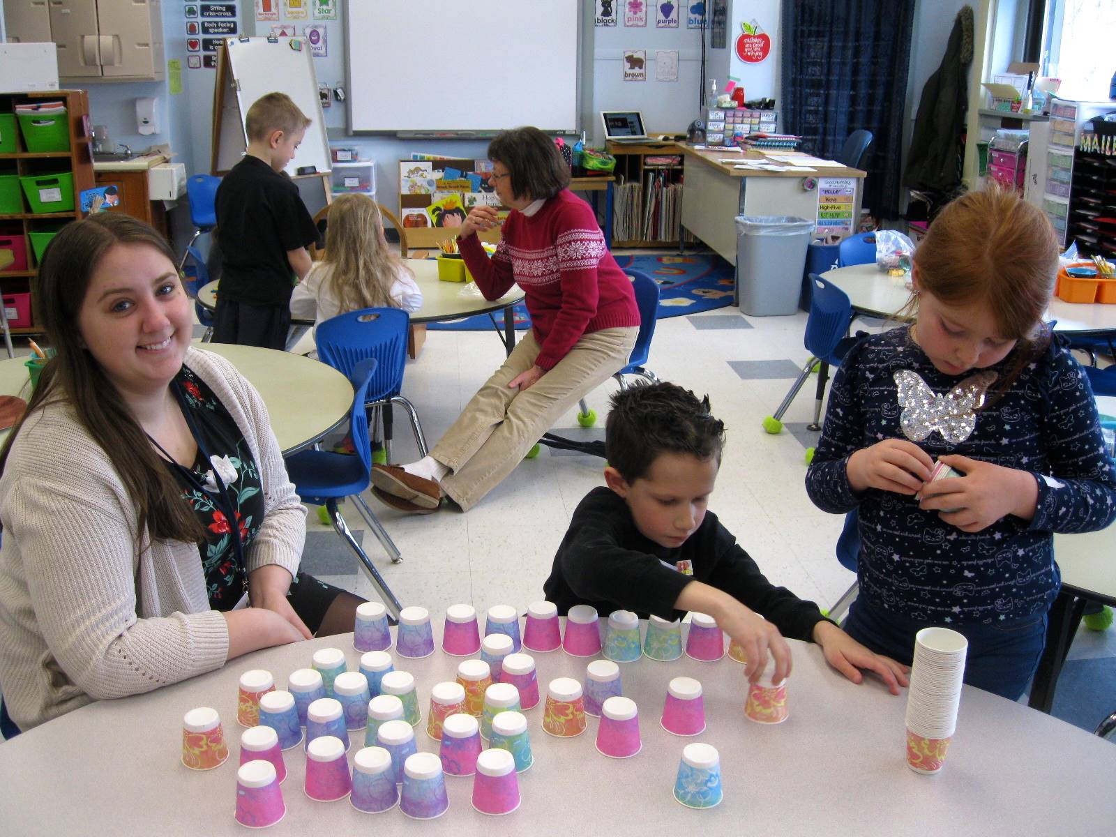 2 students and a teacher create a pyramid out of 100 dixie cups.