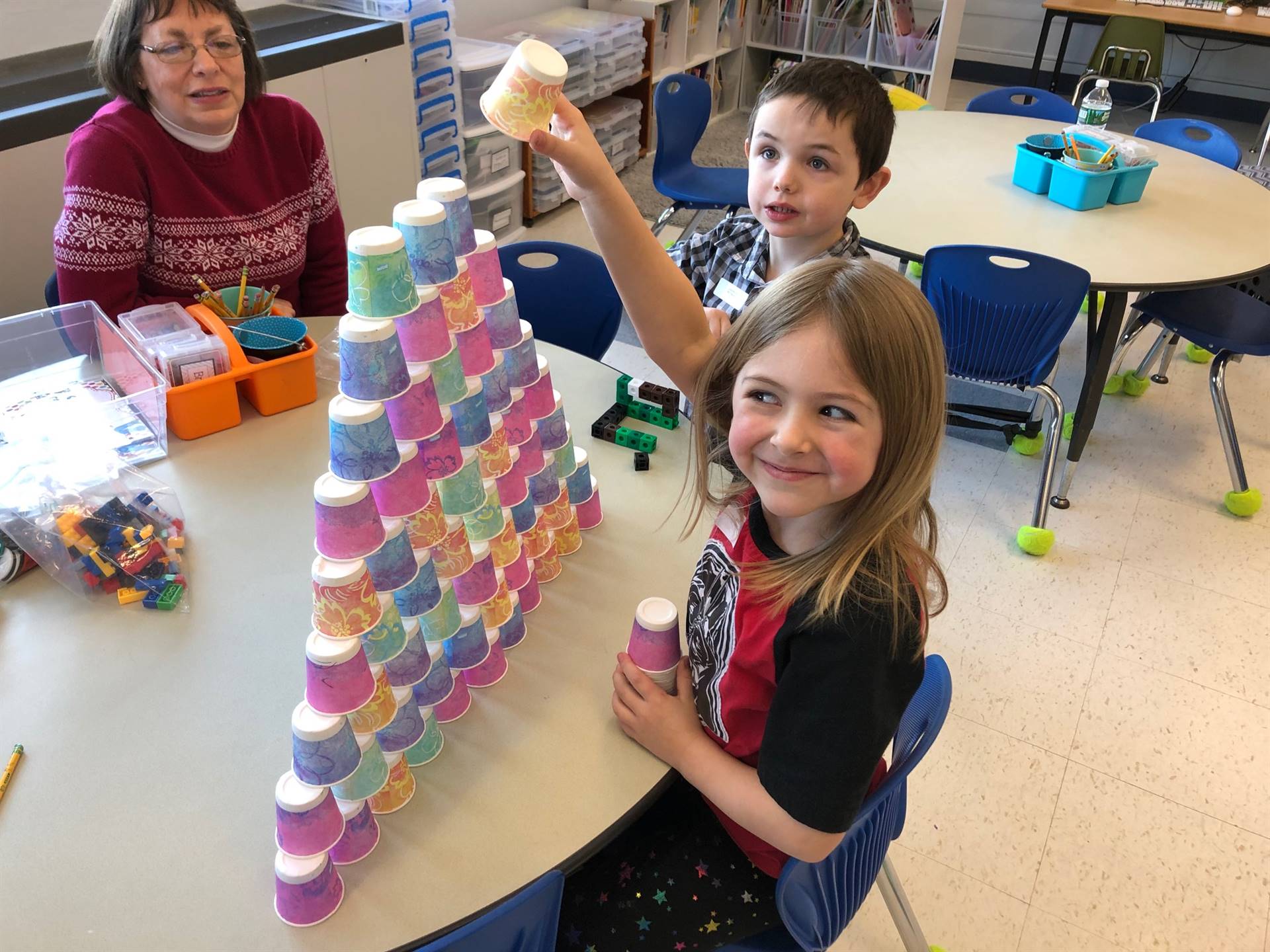 2 students  and an adult with 100 dixie cup pyramid.