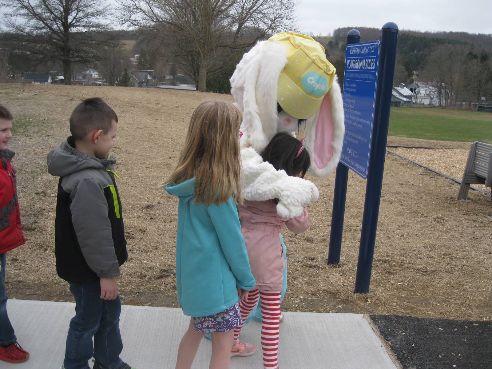 Easter Bunny hugs a student while 2 others wait their turn.