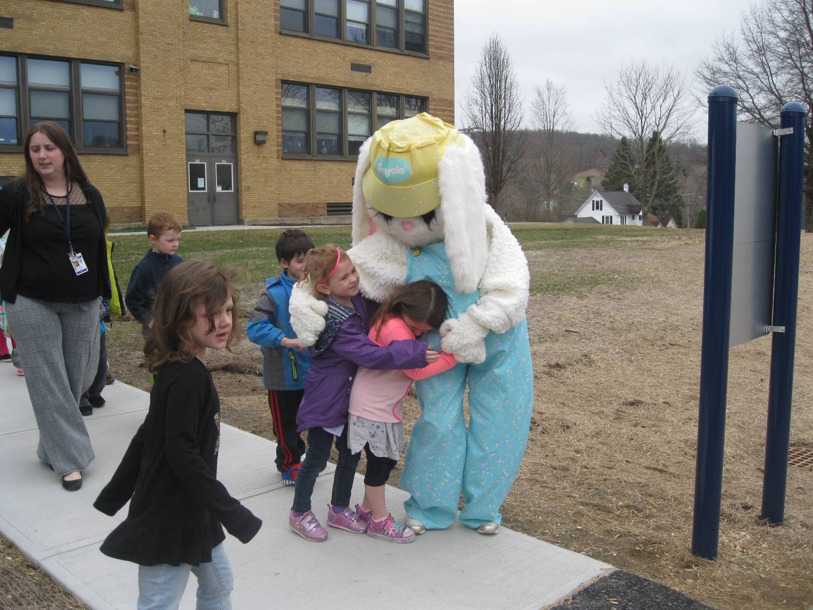 Students hug Easter Bunny while others watch.