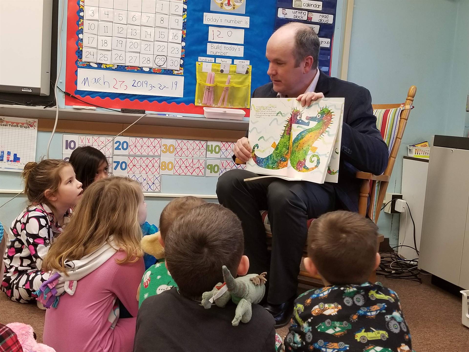 First grade students listen to Mr. Ryan read.