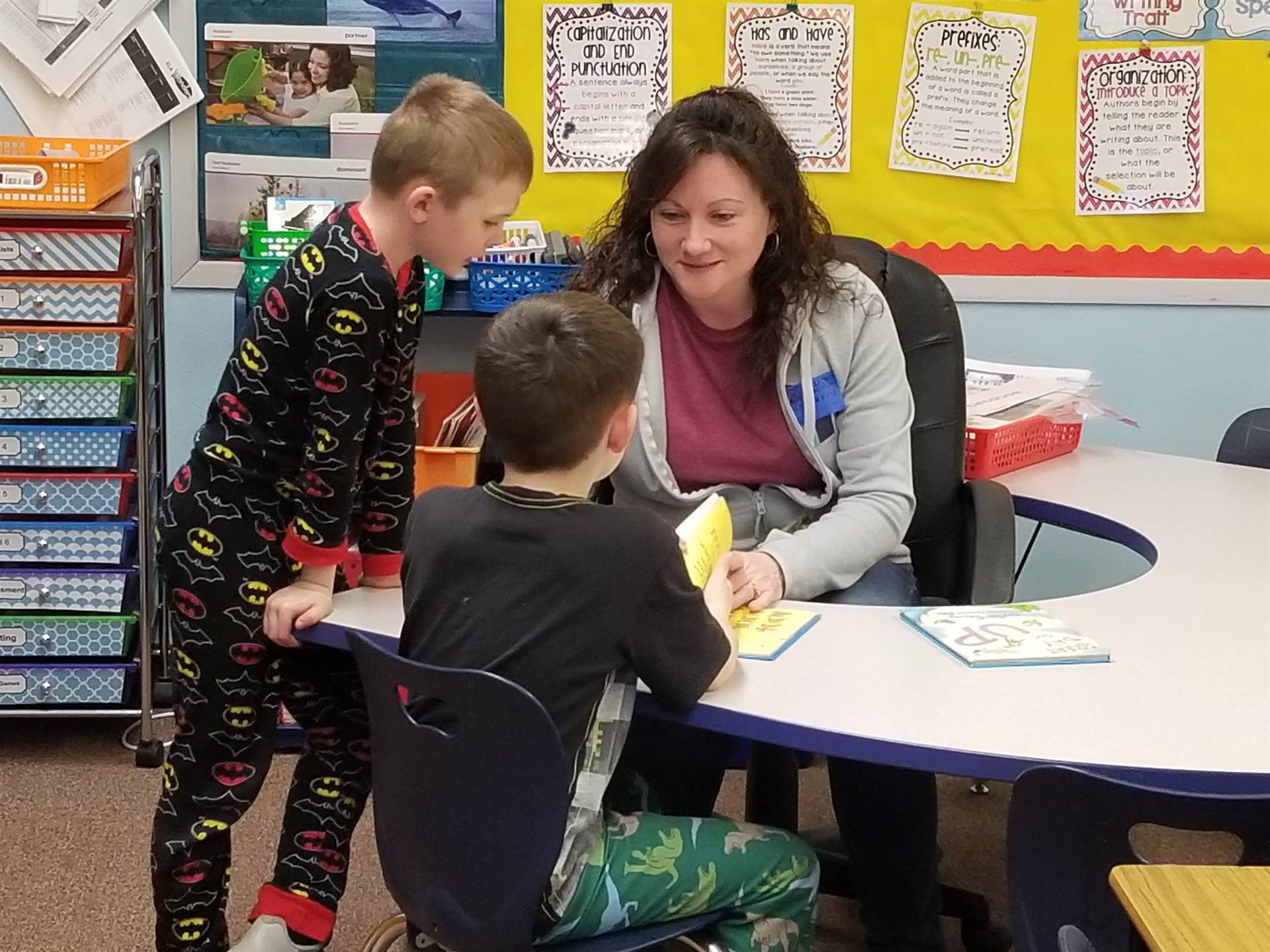 A parent listens to 2 students read.