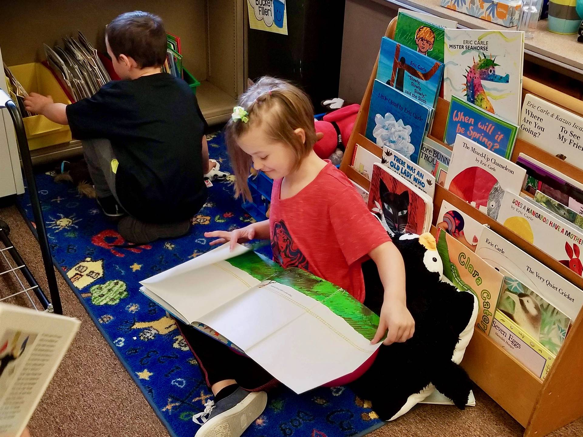 A student gets a book from shelf and another one reads.