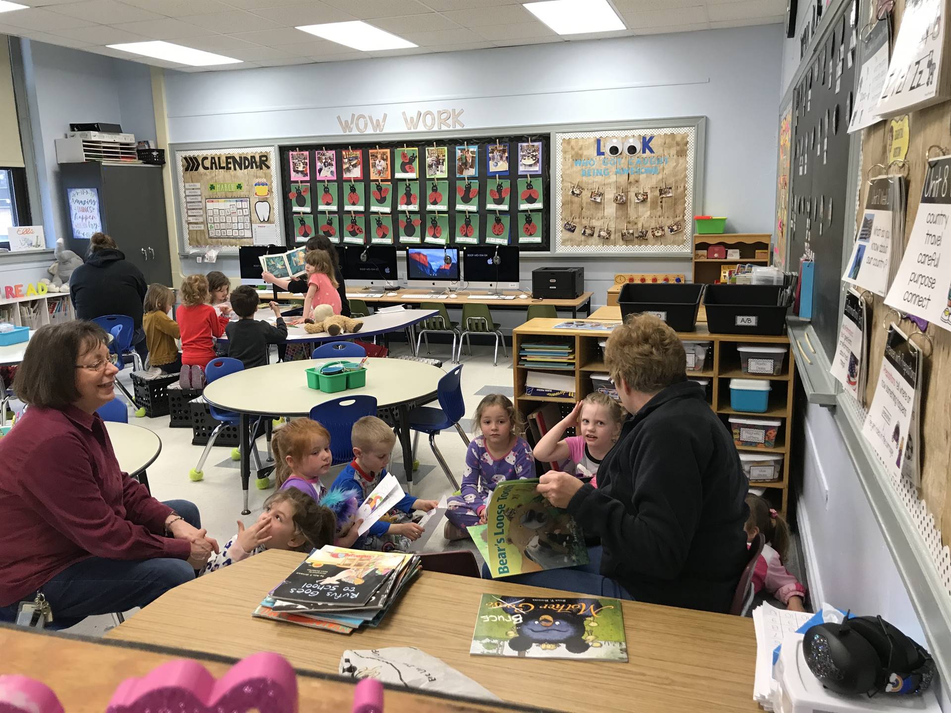 a parent and staff member read with students.