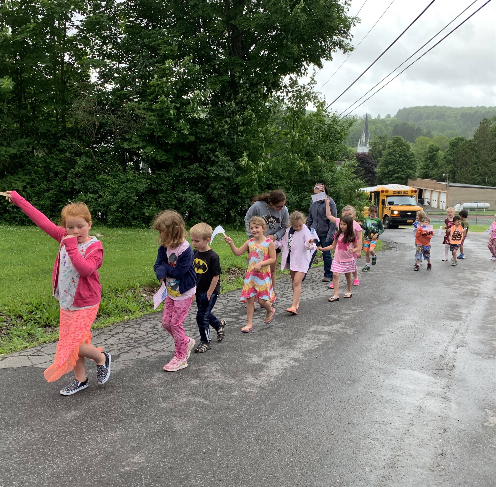 Students hold up flags and march in flag day parade.