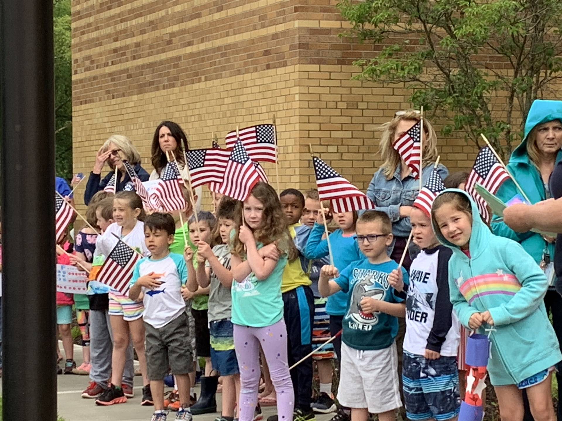 Students wave flags around the flagpole for flag day.