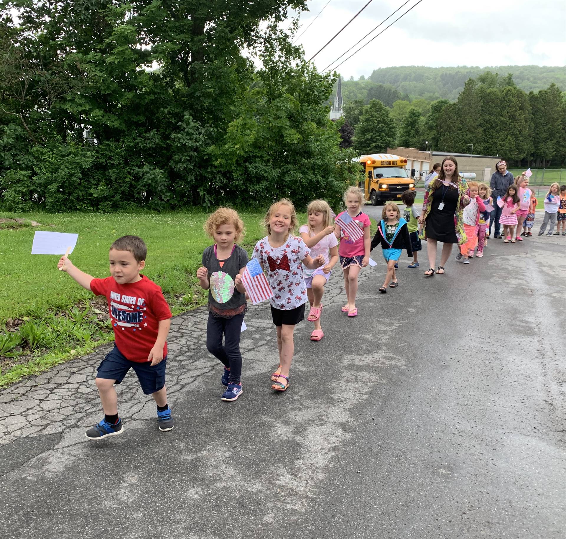 Students hold up flags and march in flag day parade.