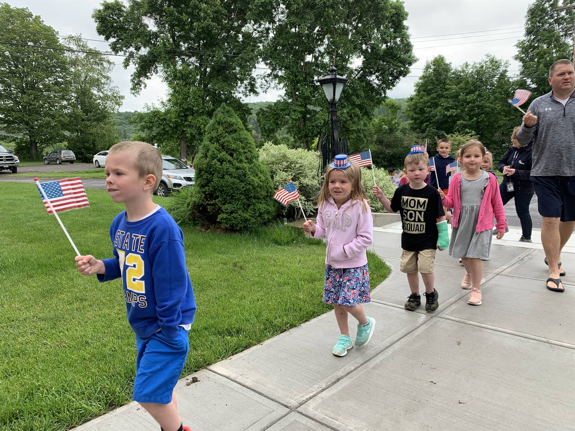 Students hold up flags and march in flag day parade.