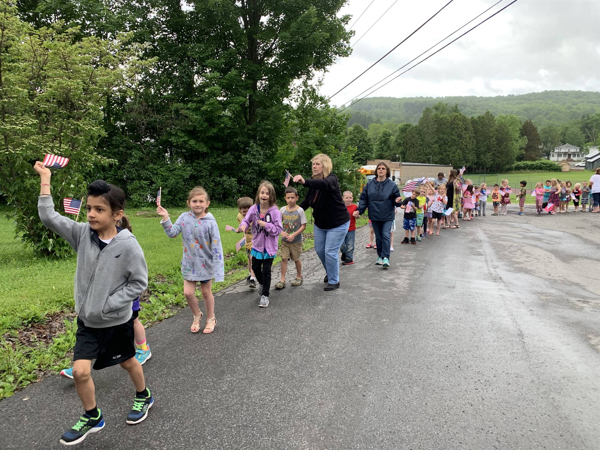 Students hold up flags and march in flag day parade.