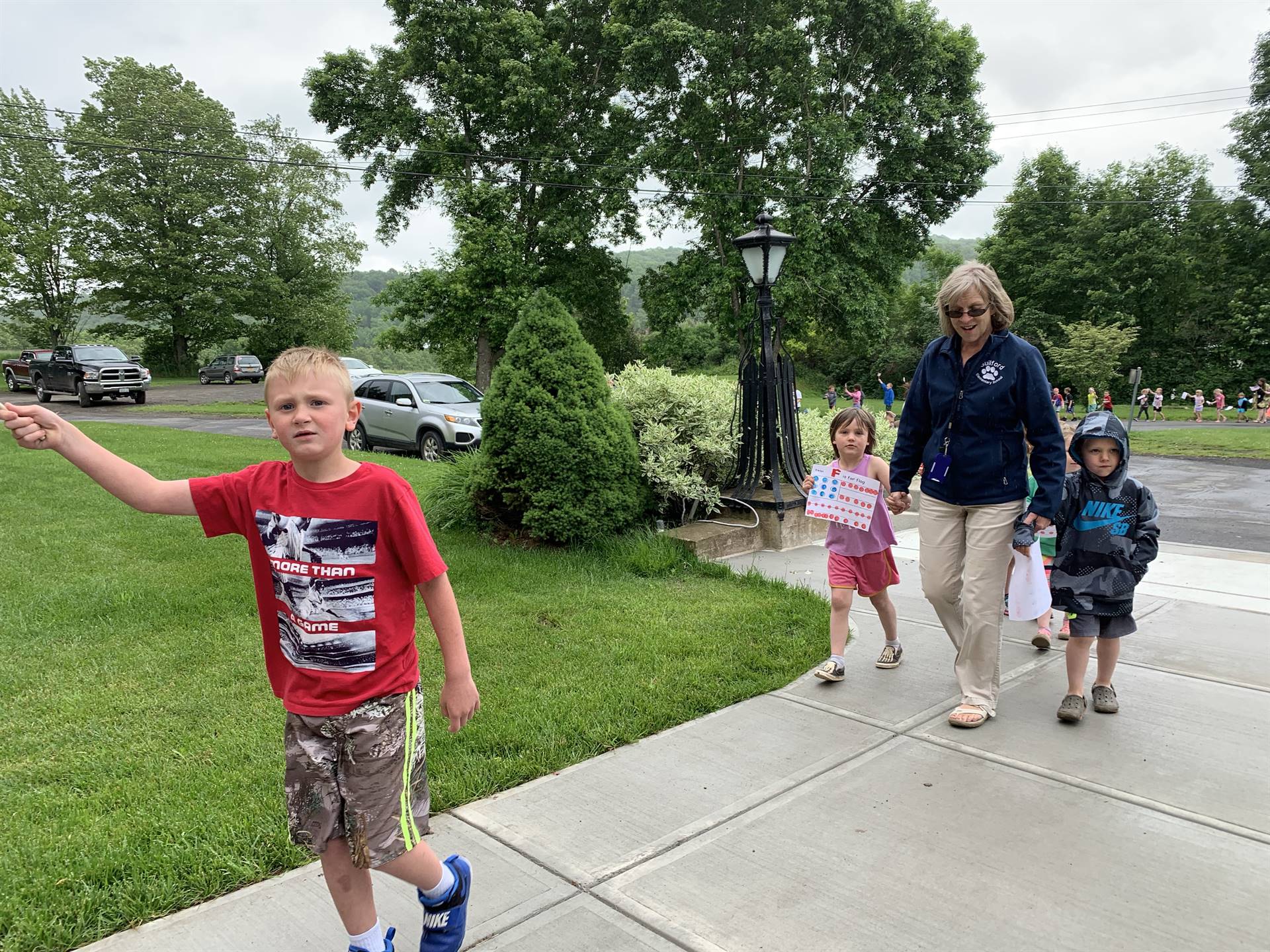 Students hold up flags and march in flag day parade.