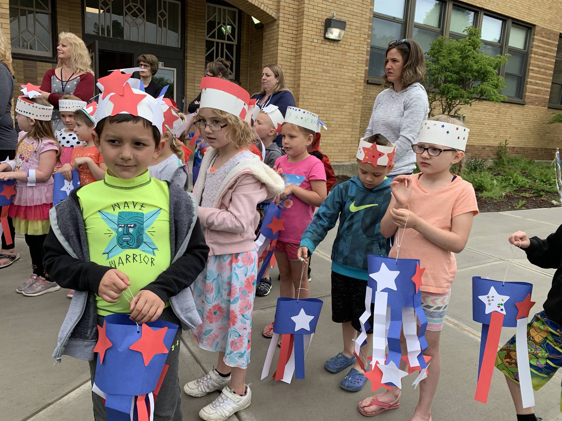 Students hold up flags and march in flag day parade.