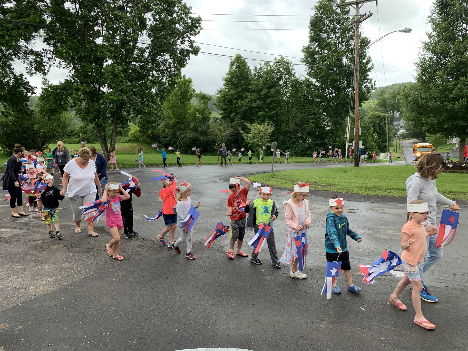 Students hold up flags and march in flag day parade.