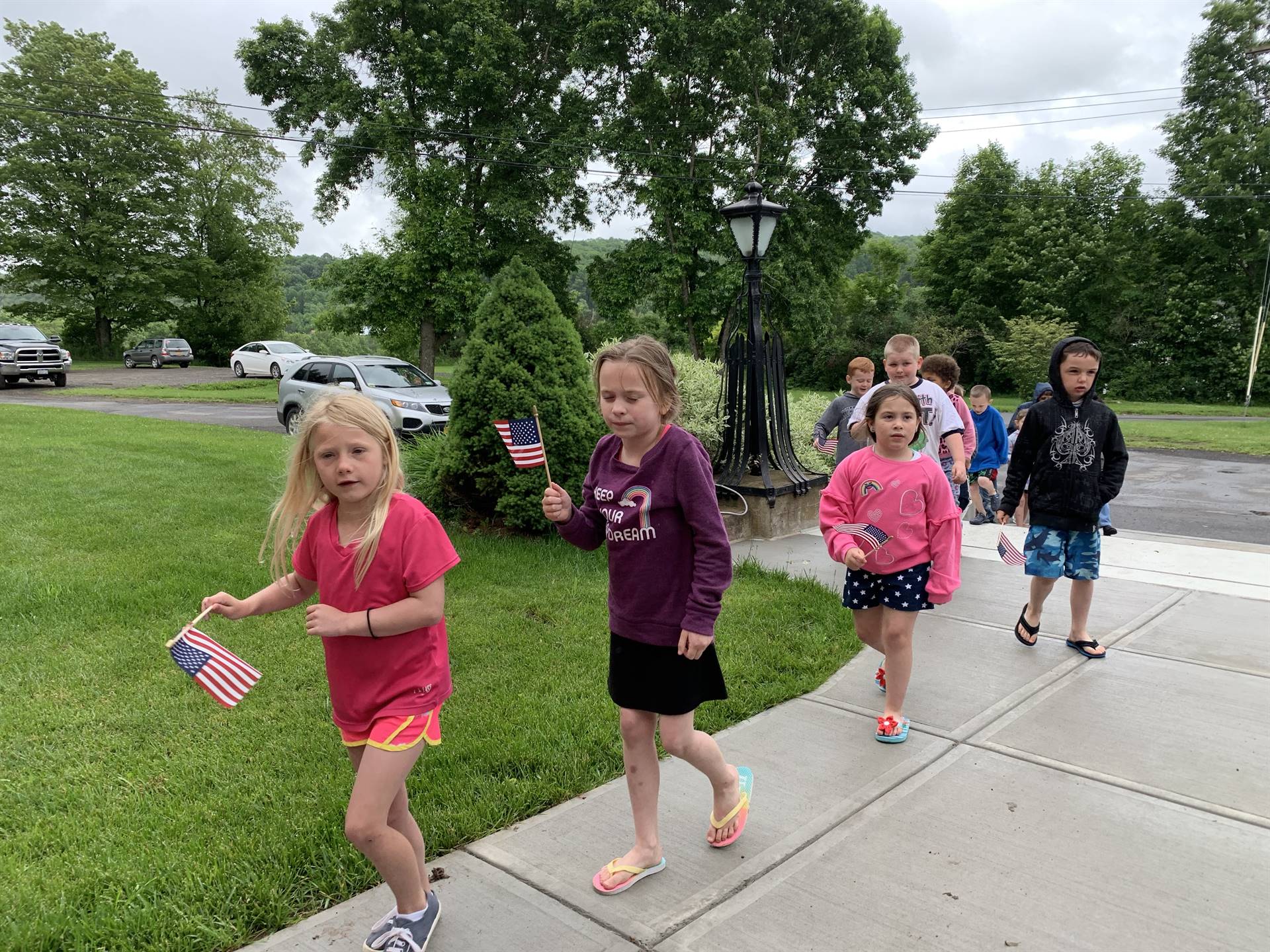 Students hold up flags and march in flag day parade.