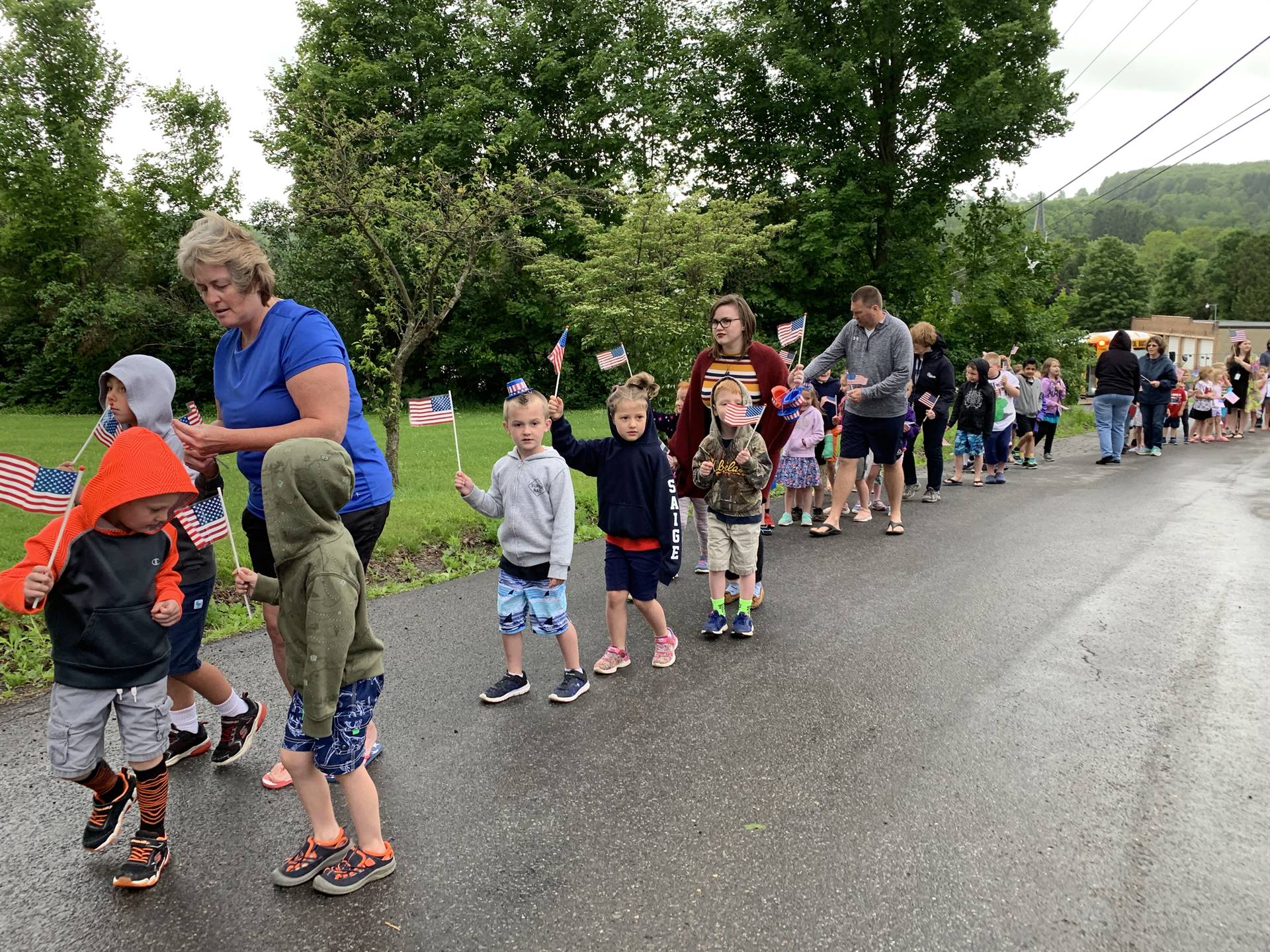 Students hold up flags and march in flag day parade.