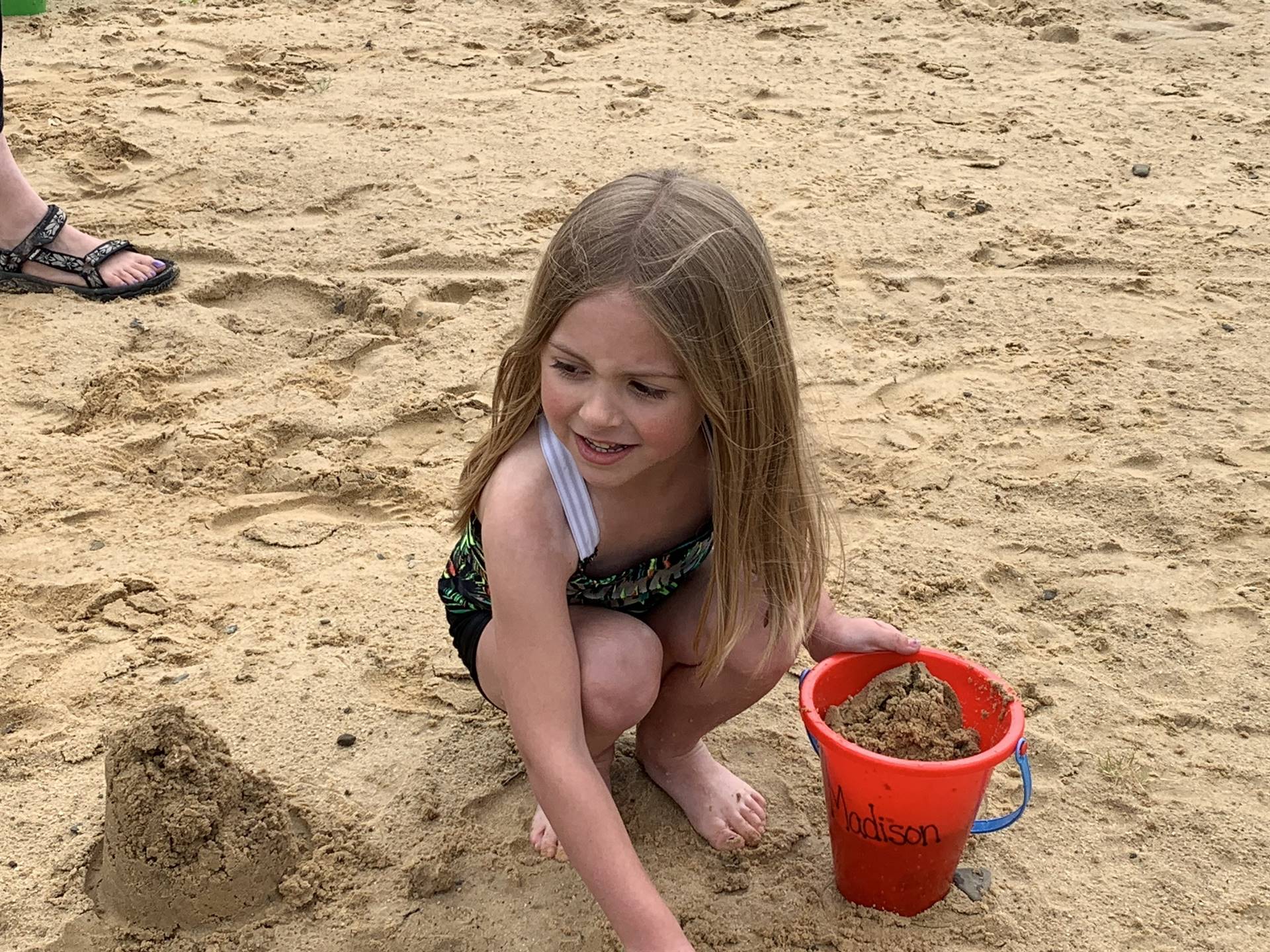 1 student with her pail in the sand.