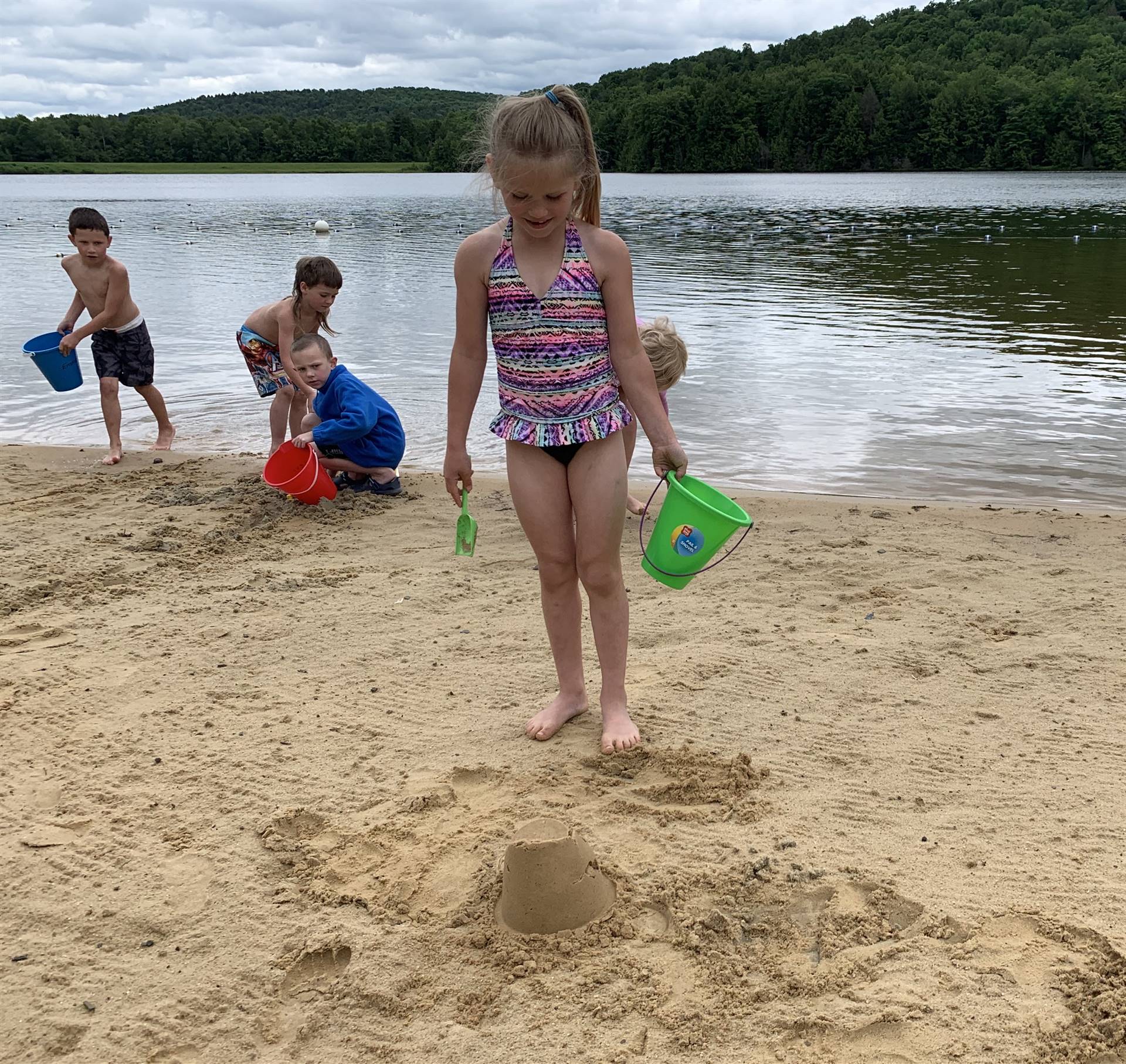 A student with a pail on the sand.