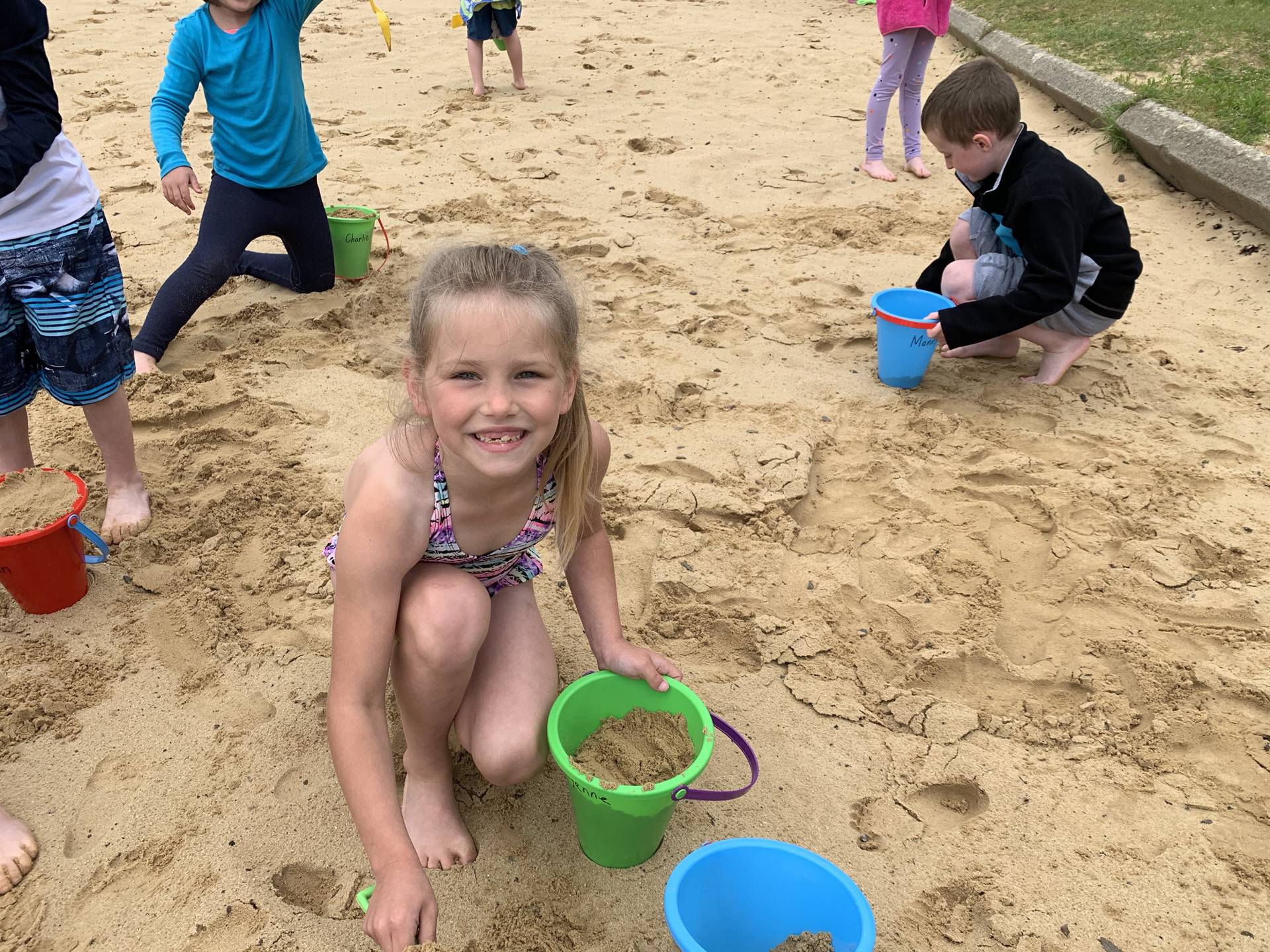 A student with a pail on the sand.