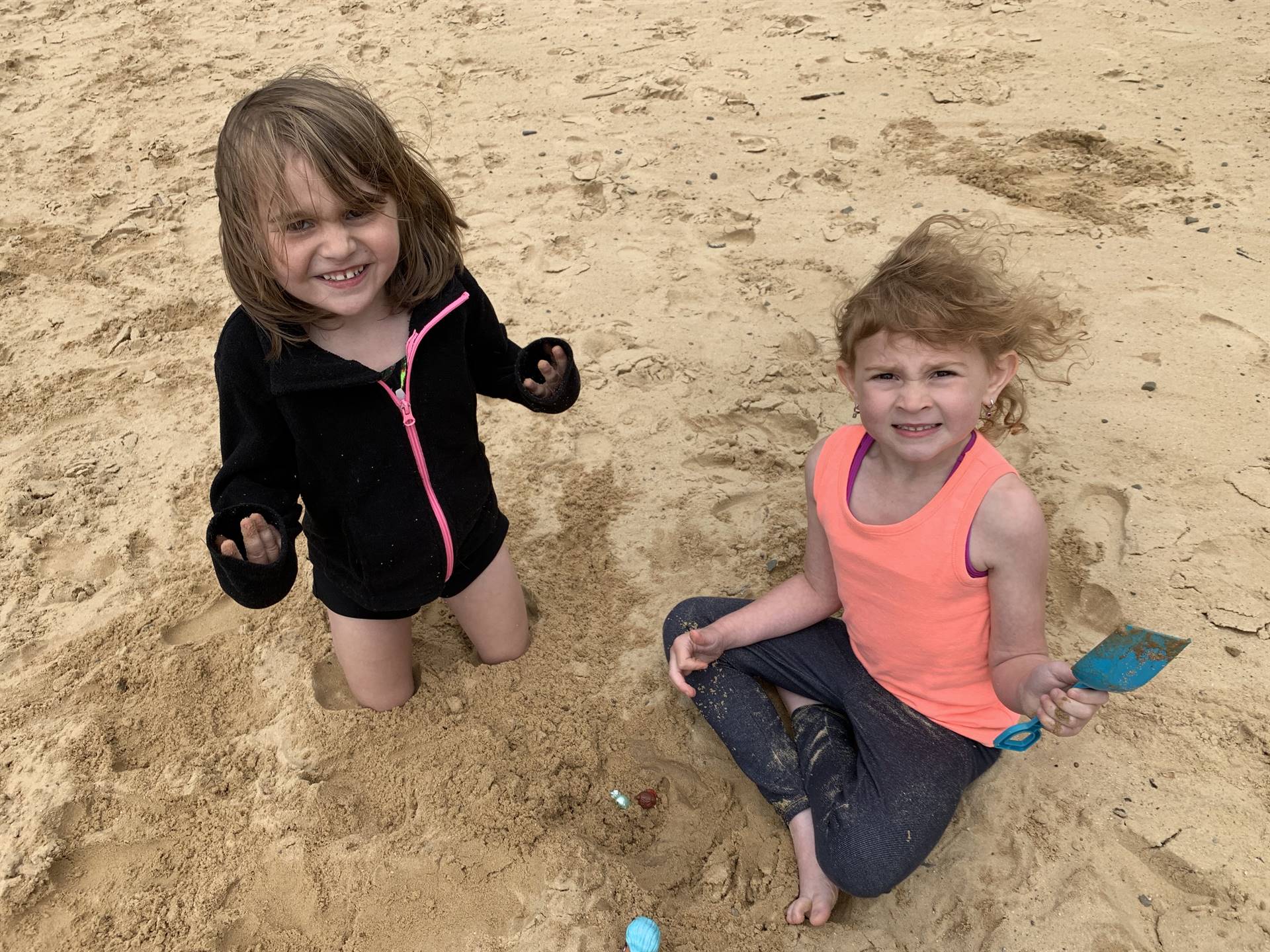 2 students play in sand together.