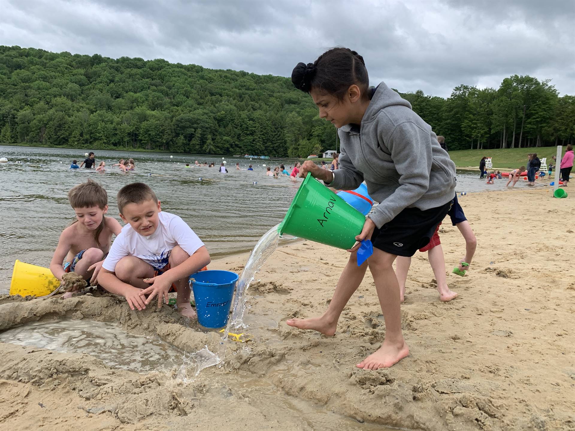 students pouring water in sand.