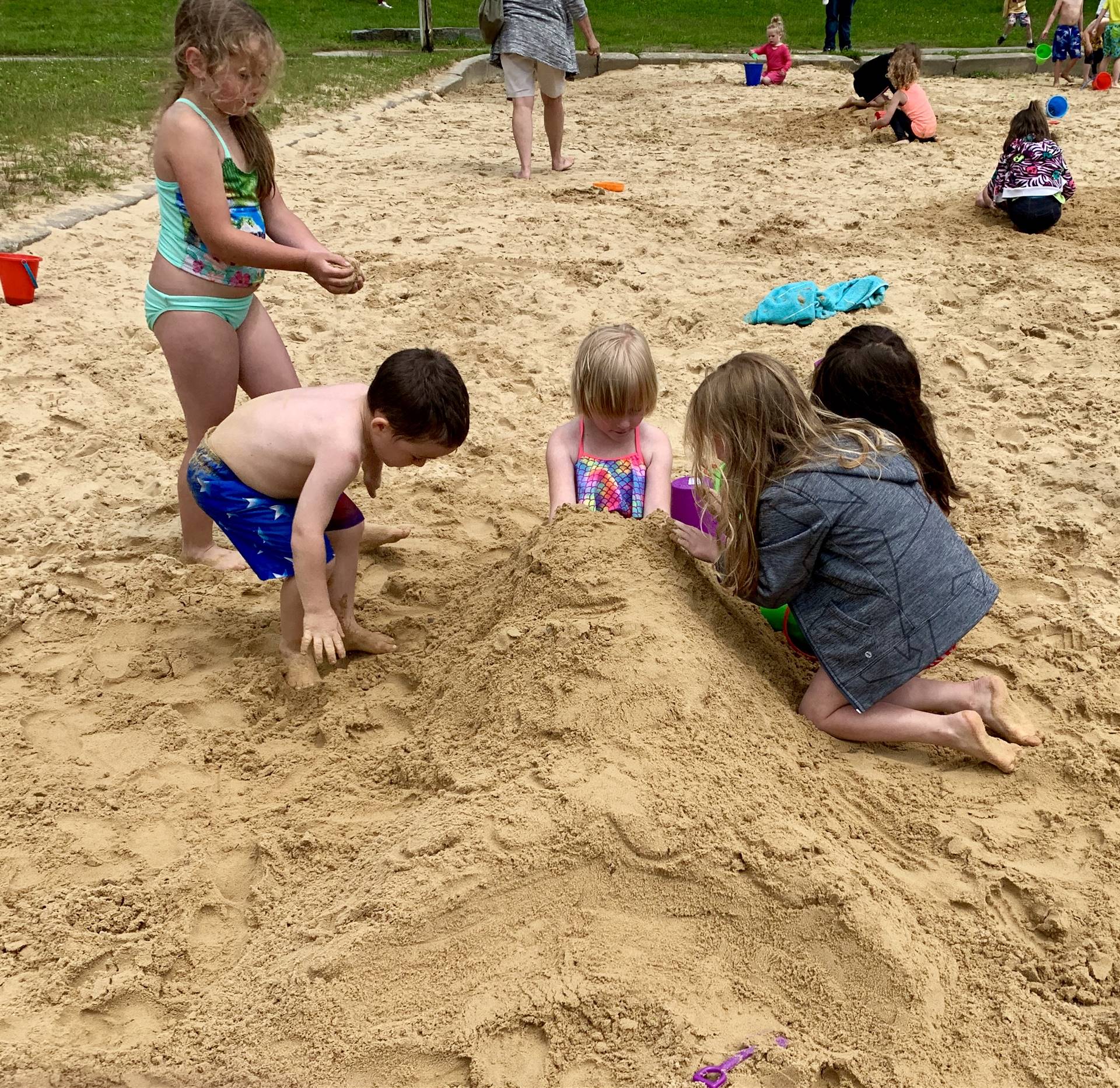 A group of student burying someone in sand.