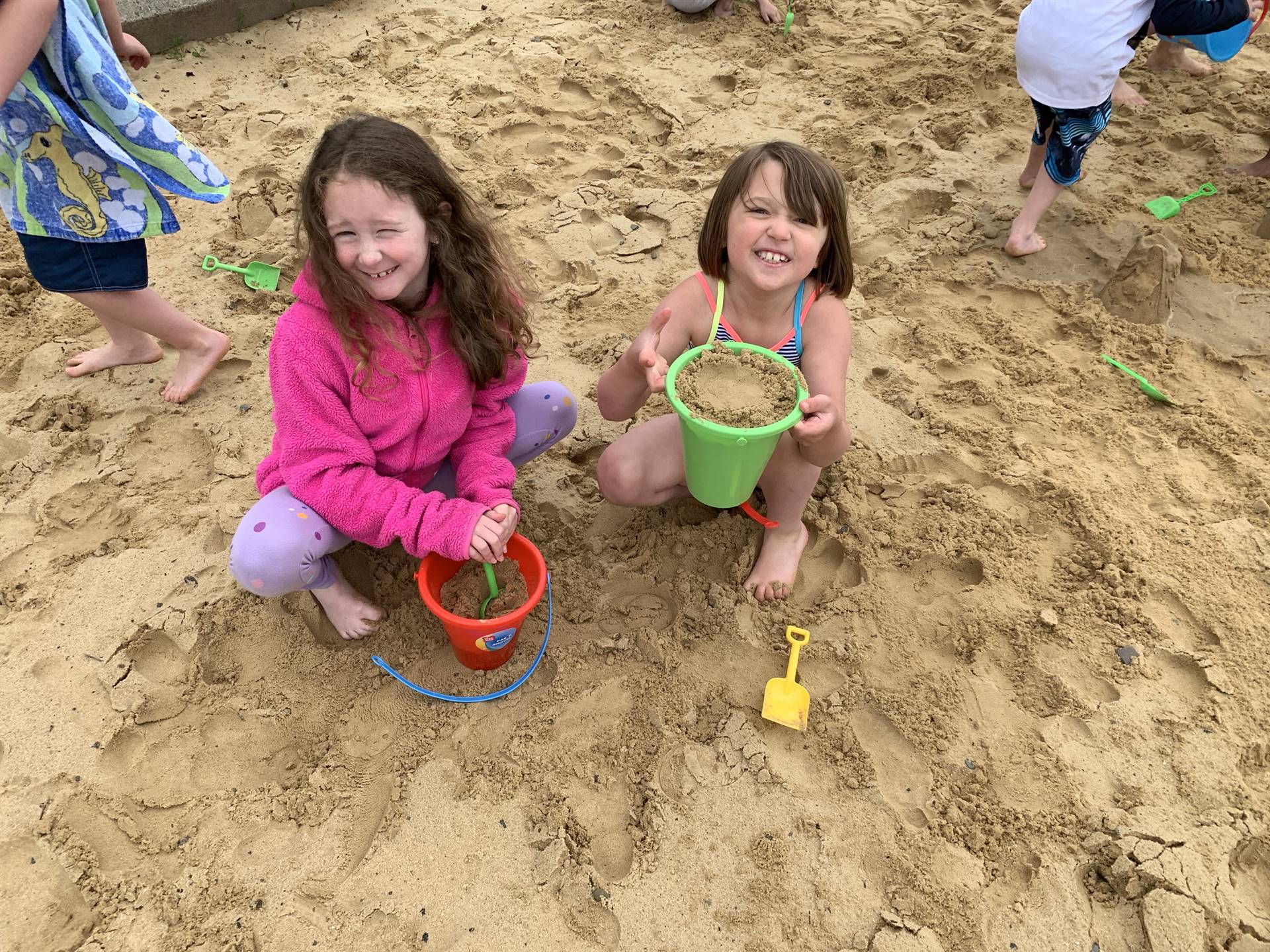2 students play in sand.