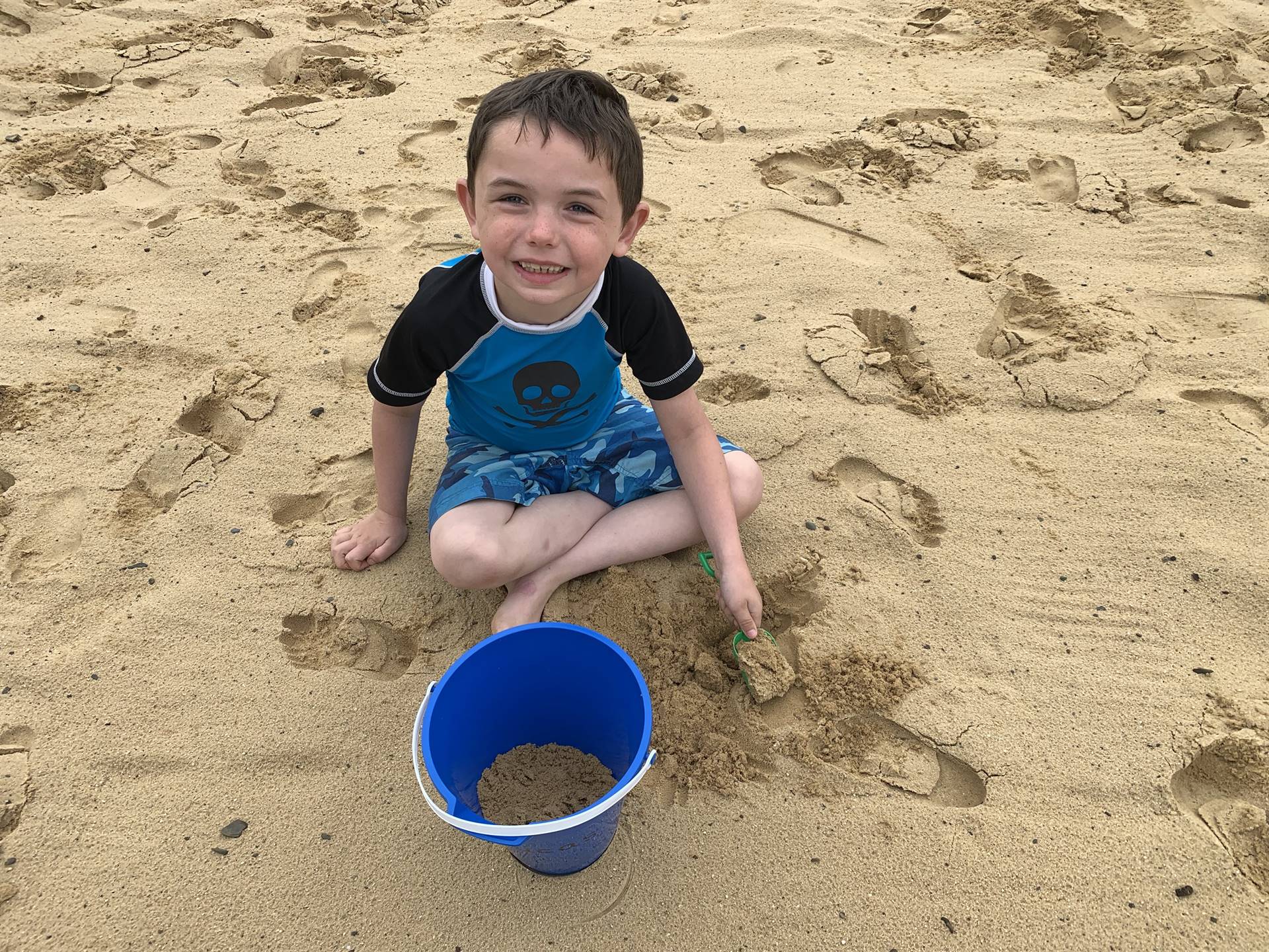 A student with his bucket and lots of sand.