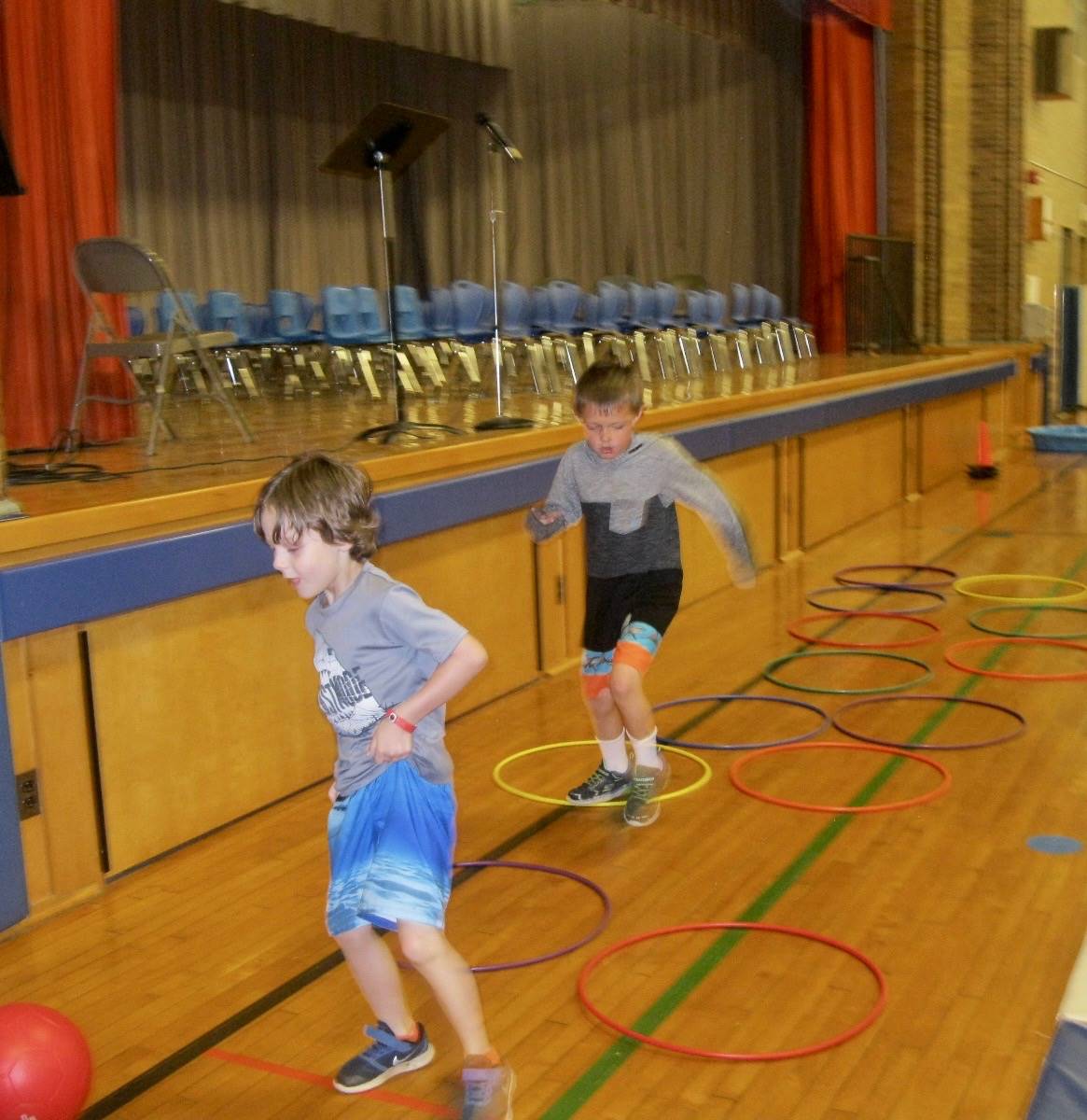 2 students walk on hula hoops.