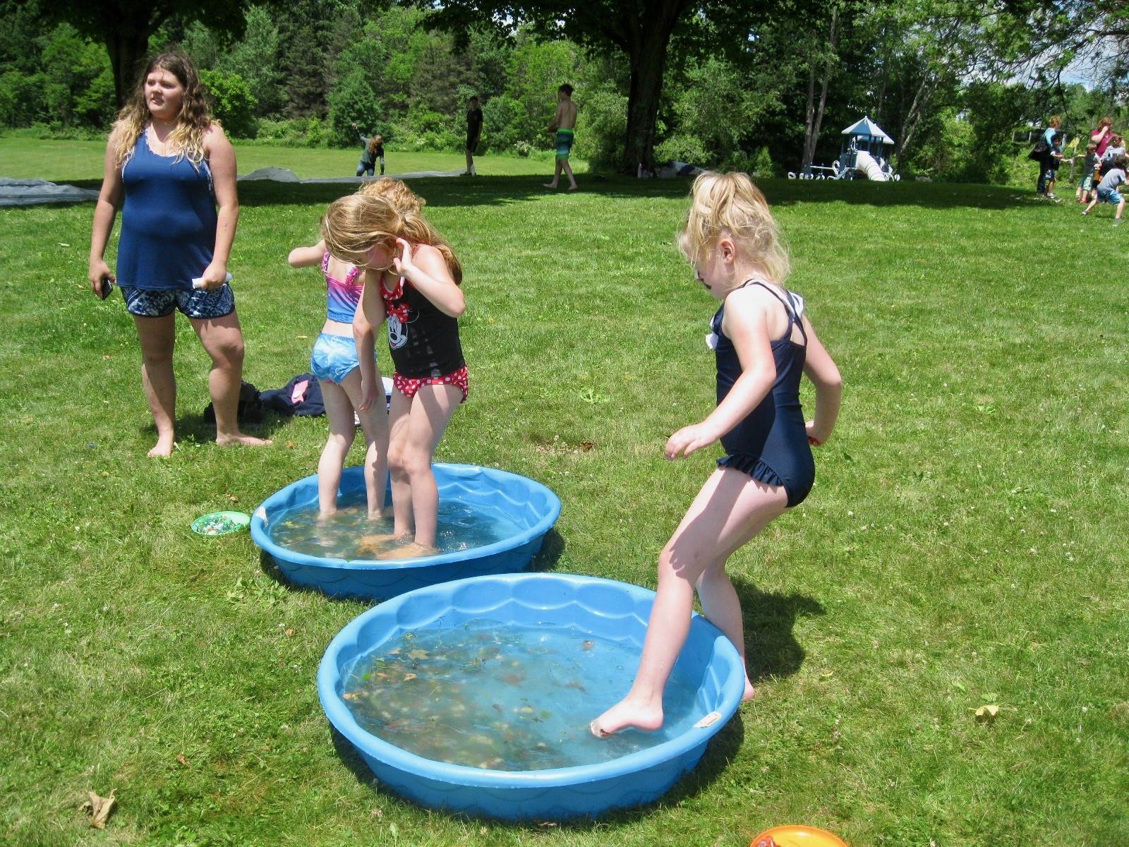3 students use toes to get marbles out of a wading pool.