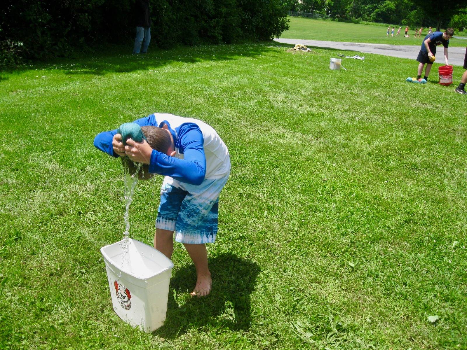 A student squeezes sponge over his head.