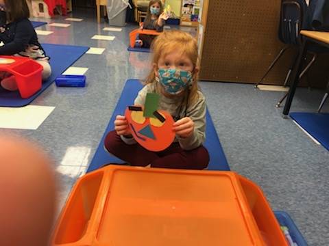 student holds up pumpkin and makes a matching emotion face.