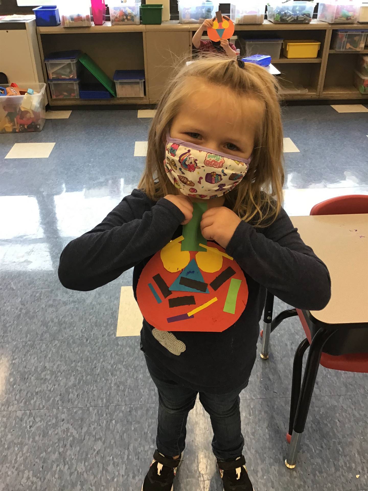 student holds up pumpkin and makes a matching emotion face.